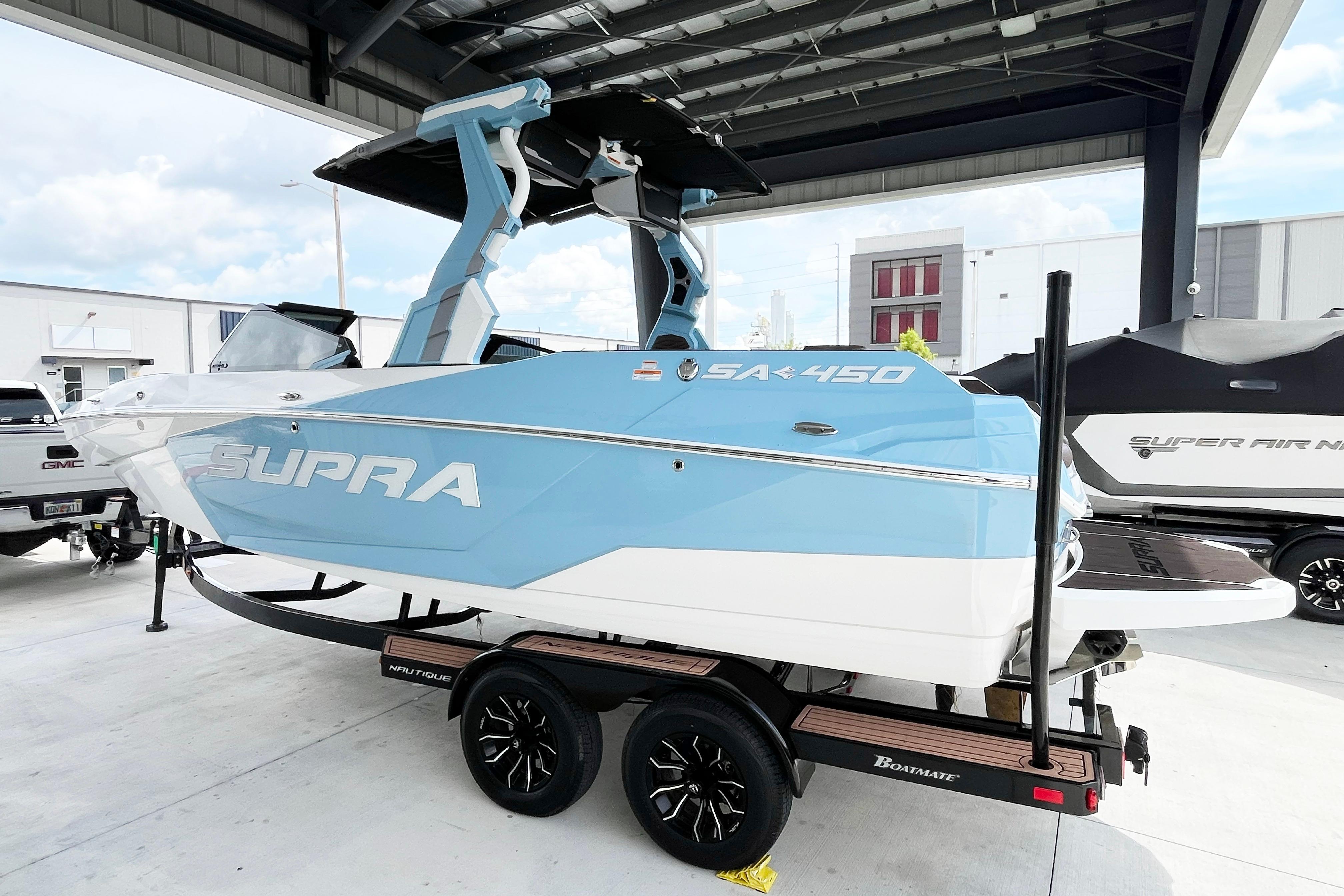 2025 Supra SA450 boat in blue and white on a trailer under a canopy.