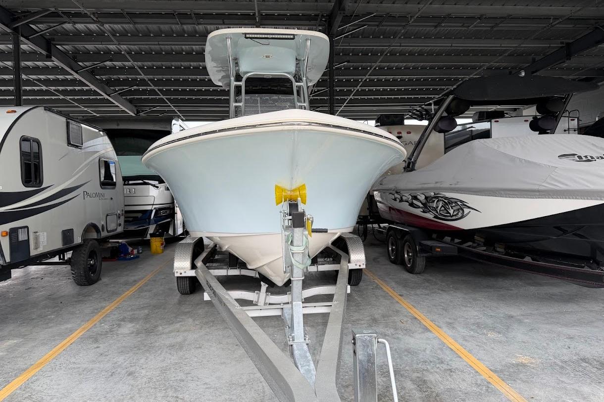 2024 Key West 219 FS boat on trailer, parked in covered storage between RVs.