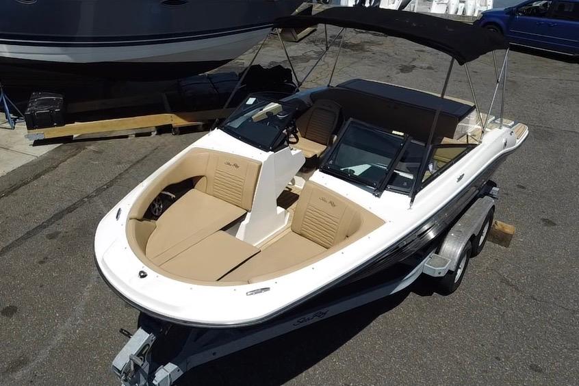 2021 Sea Ray SPX 190 boat with tan seating and black canopy on a trailer.