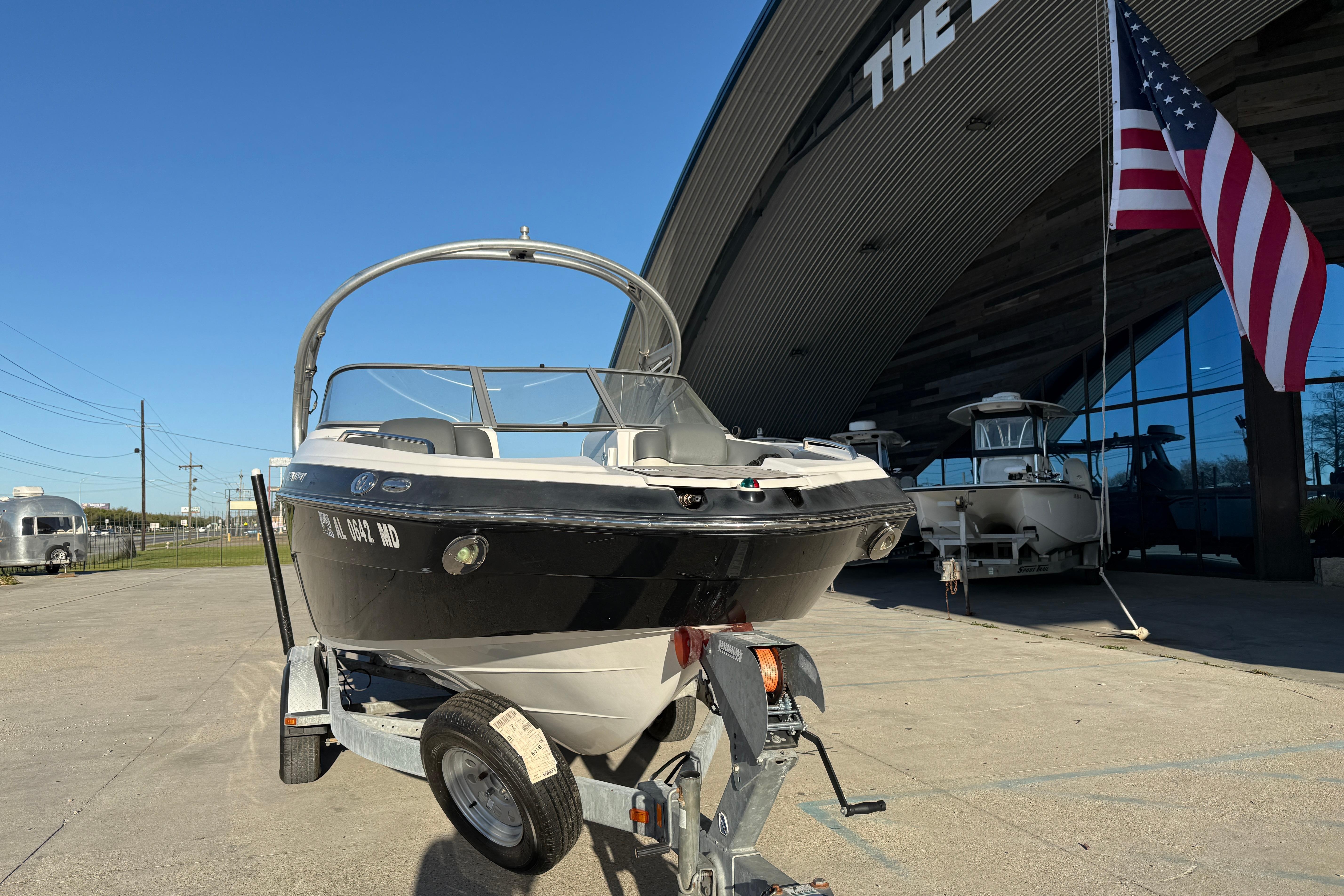 2011 Yamaha Boats 242 Limited S on trailer outside dealership with American flag.