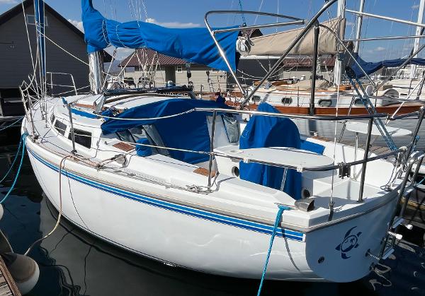 1980 Catalina 30 sailboat docked, featuring blue covers and sleek white hull.