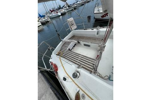 1986 Beneteau First 305 sailboat docked at marina, showcasing deck and seating area.