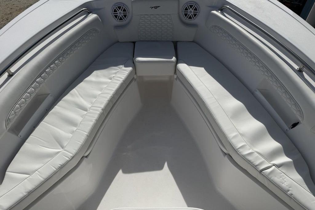 2026 Tidewater 232 LXF boat interior with white cushioned seating and speakers.