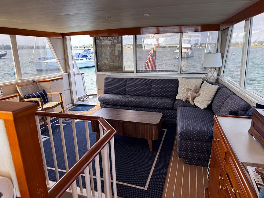 Salon of a 1961 Burger 63 yacht with sofa and table, overlooking the water.