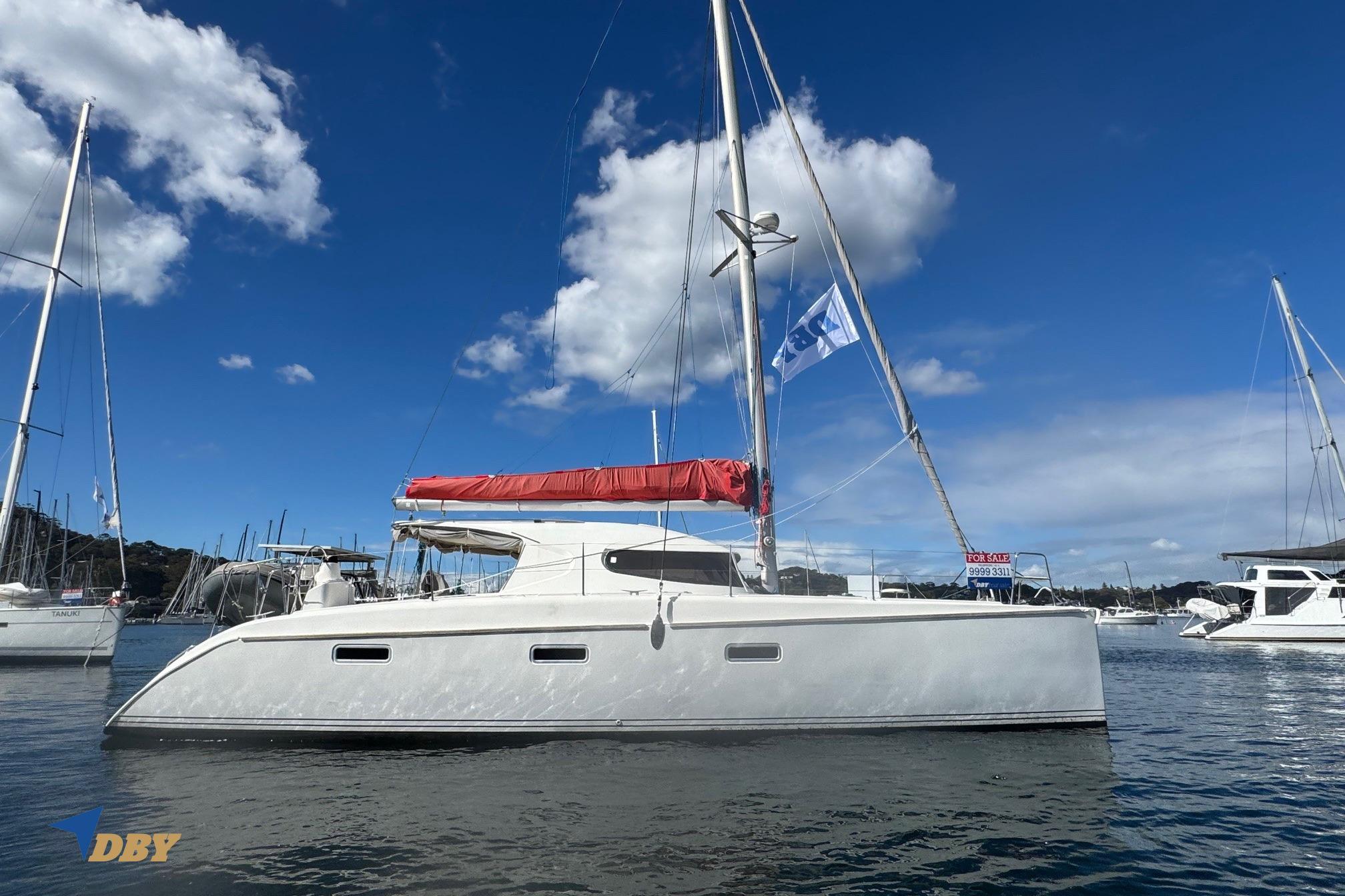 2004 Nautitech 40 Open catamaran with red sail cover, docked under blue sky.