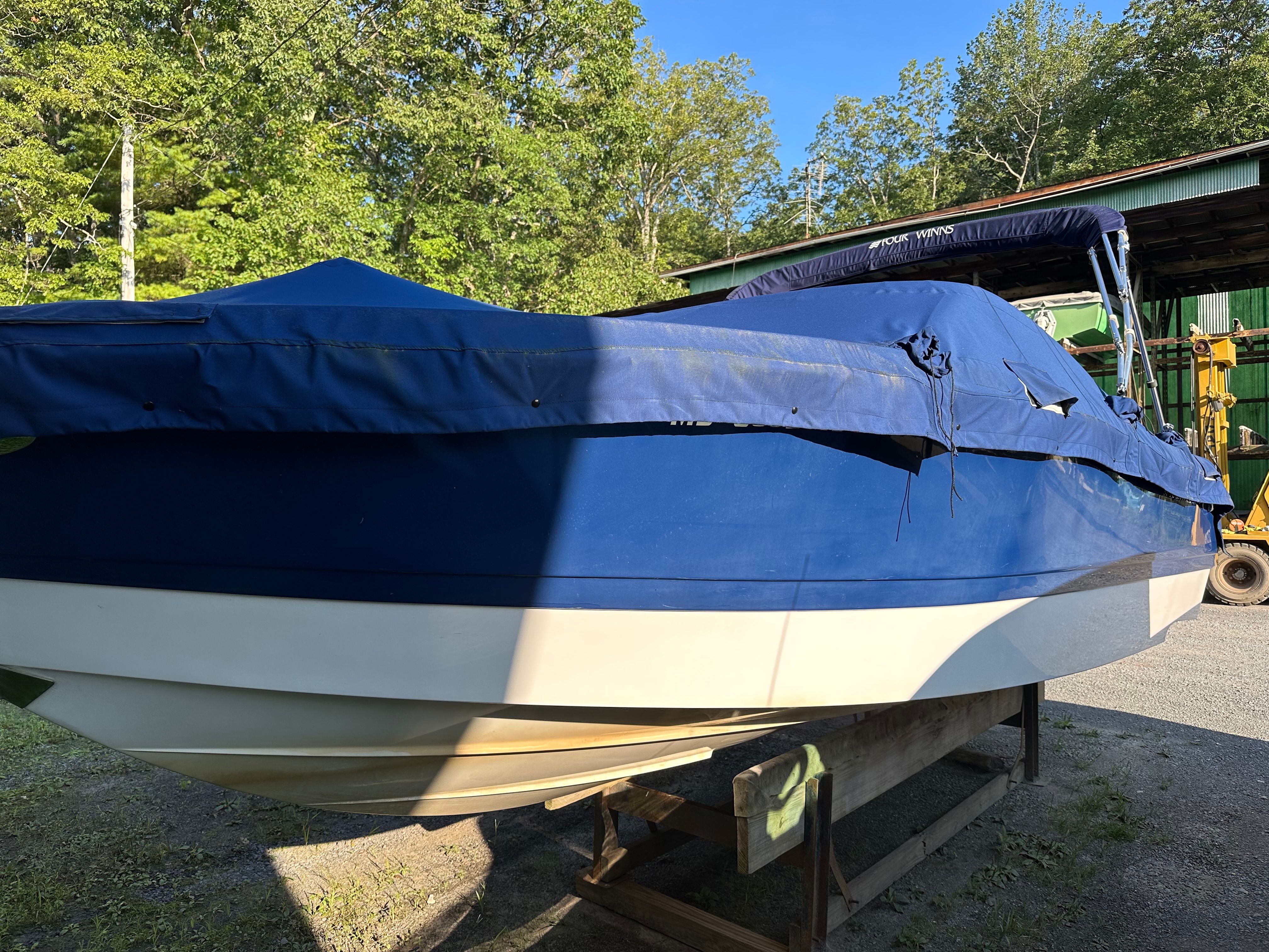 2012 Four Winns H210 boat with blue cover outdoors.