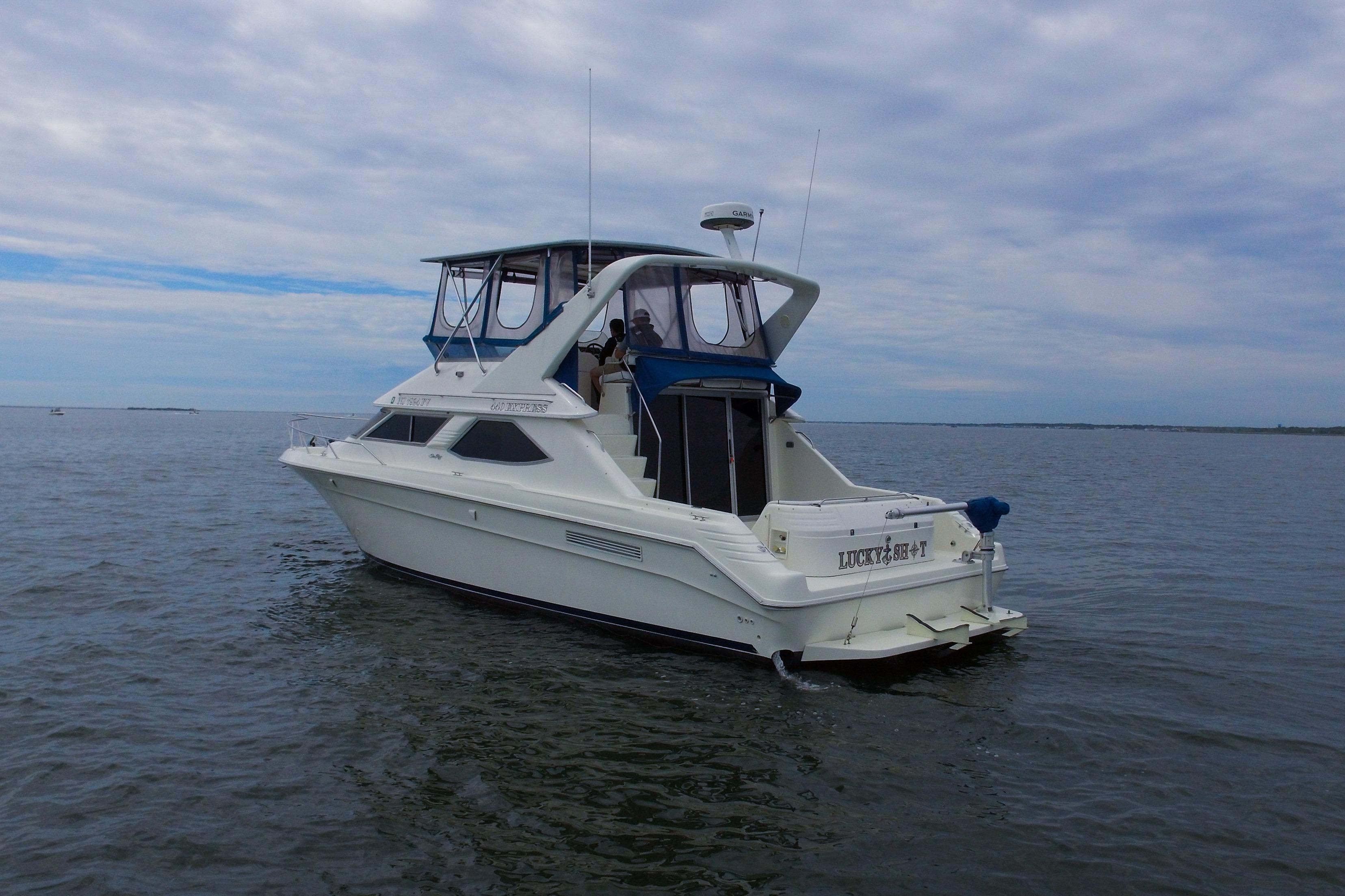 1993 Sea Ray 440 Express Bridge yacht on open water under cloudy sky.
