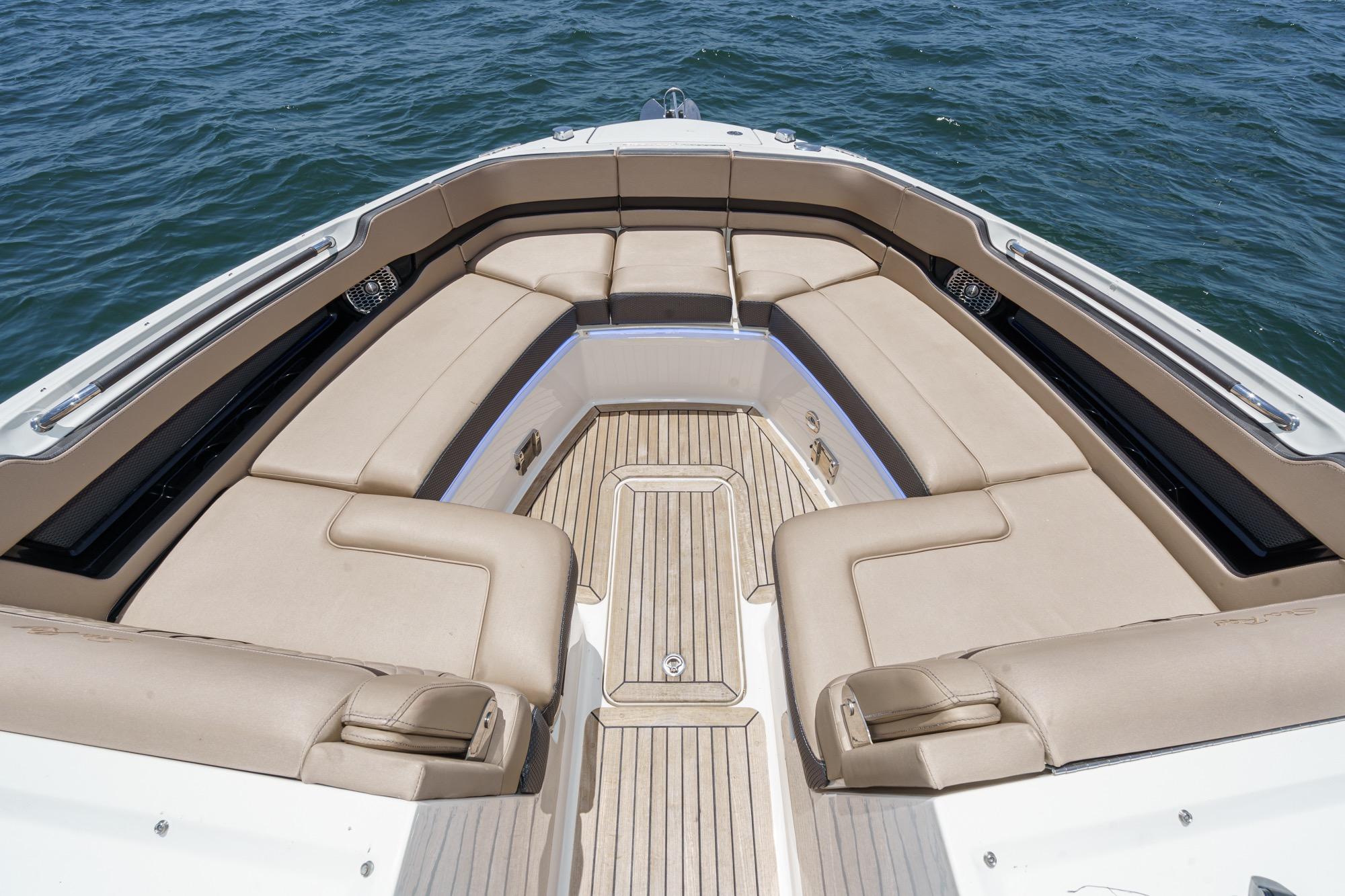 Luxurious seating area on 2018 Sea Ray SLX 310 boat, with beige upholstery and wooden flooring.