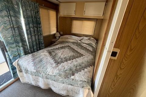 Cozy bedroom in a 1995 Myacht 40X13 houseboat with patterned bedding and wood paneling.