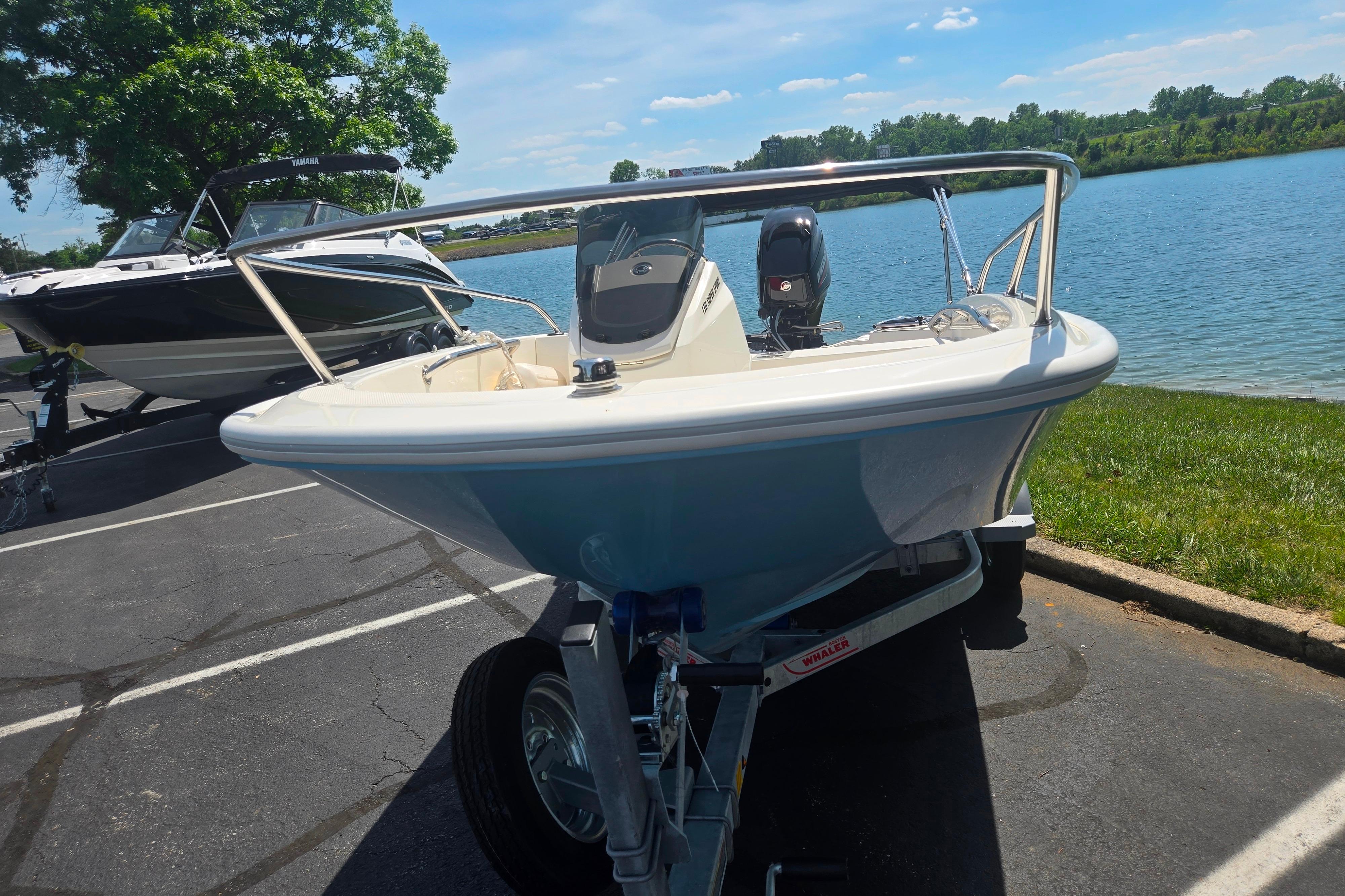 2025 Boston Whaler 130 Super Sport boat on trailer by a lake.