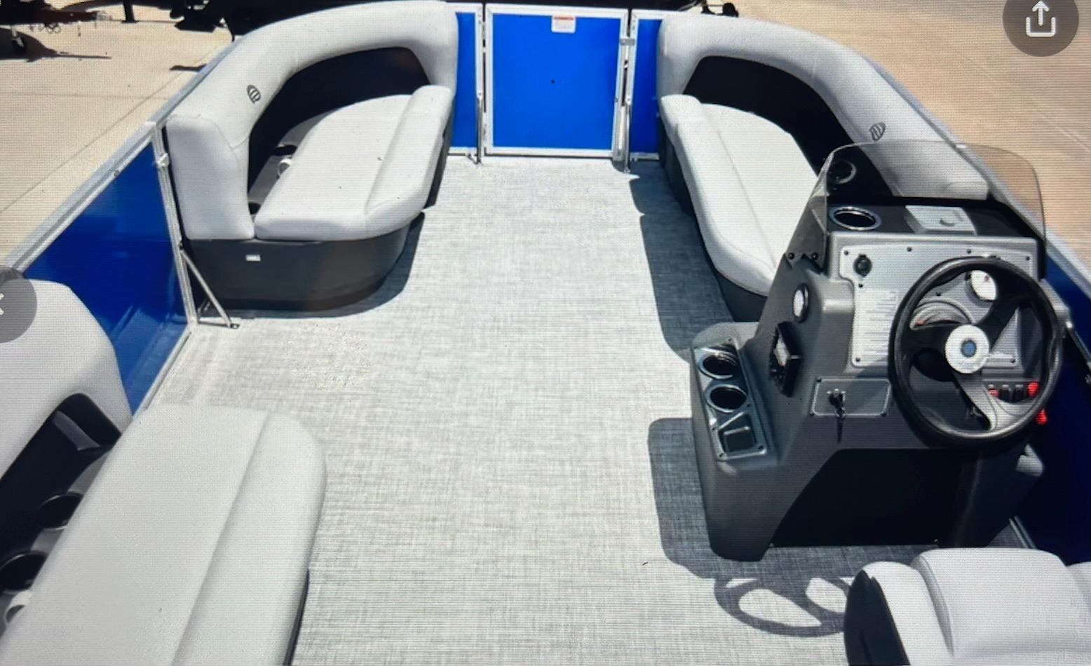2026 Sun Tracker Party Barge 16 DLX interior with gray seating and steering console.