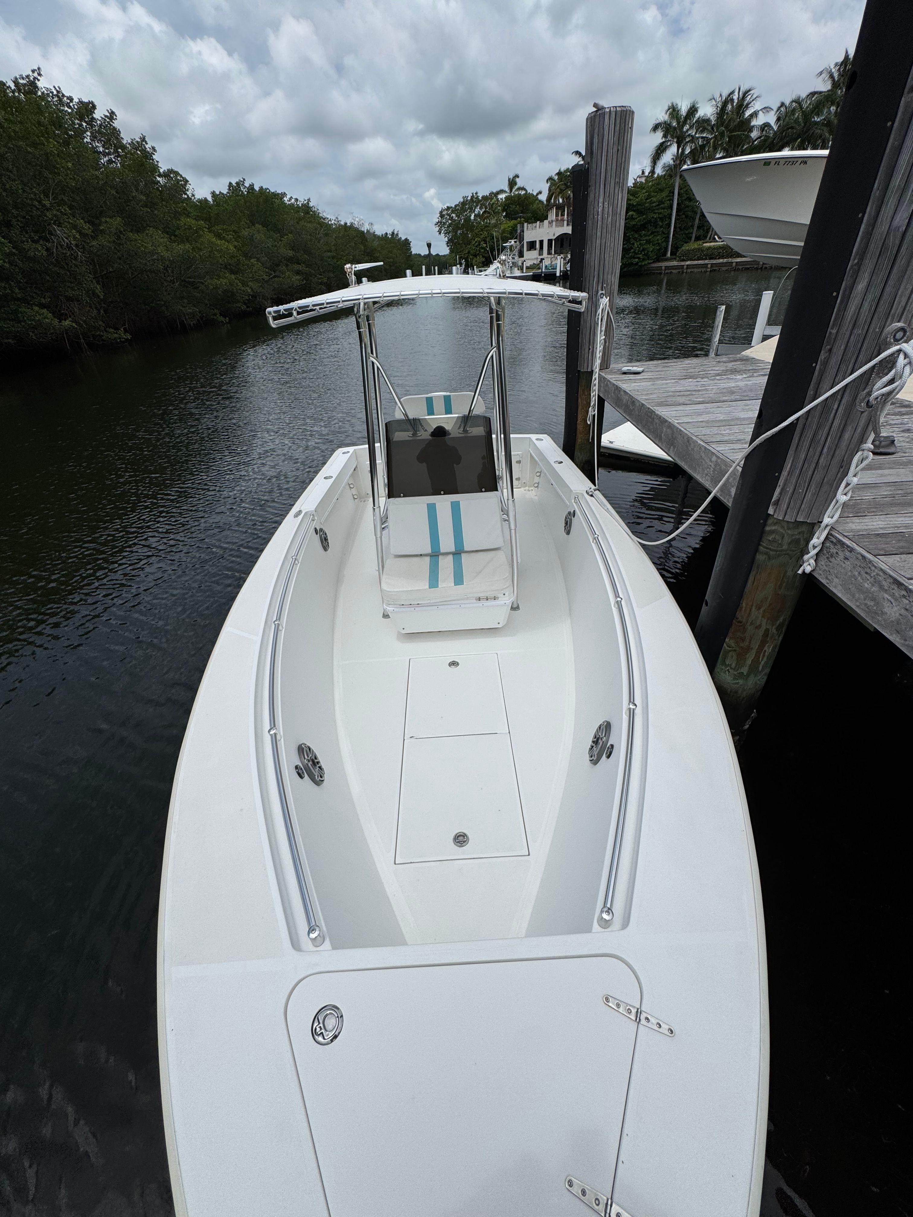 A 2004 Contender 21 boat docked at a calm pier, surrounded by trees.
