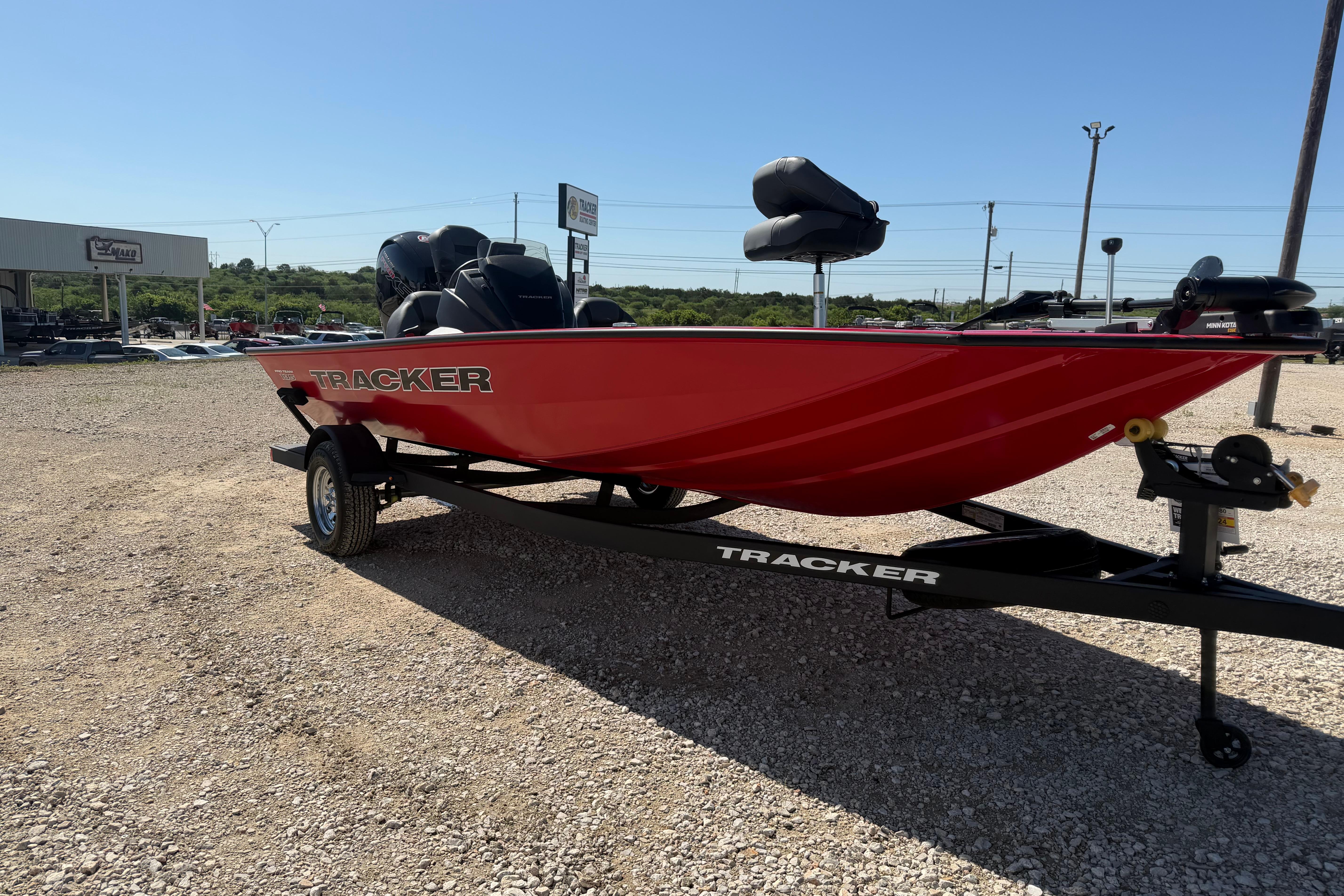 2026 Tracker Pro Team 195 boat in vibrant red on a trailer, parked outdoors.