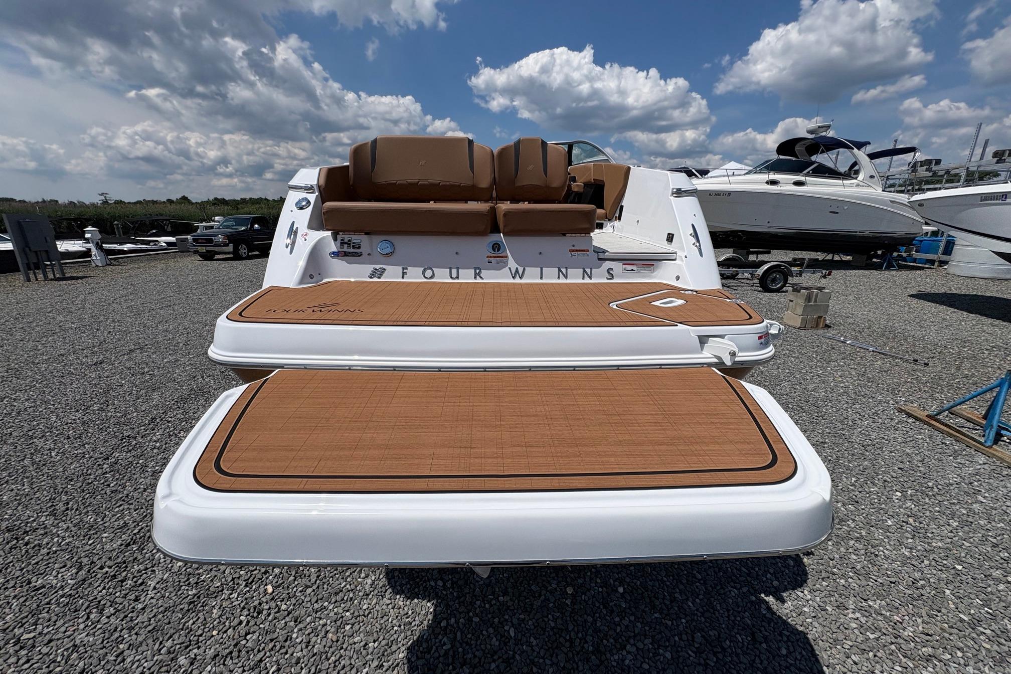 2026 Four Winns H6 boat with teak deck, displayed outdoors under a cloudy sky.