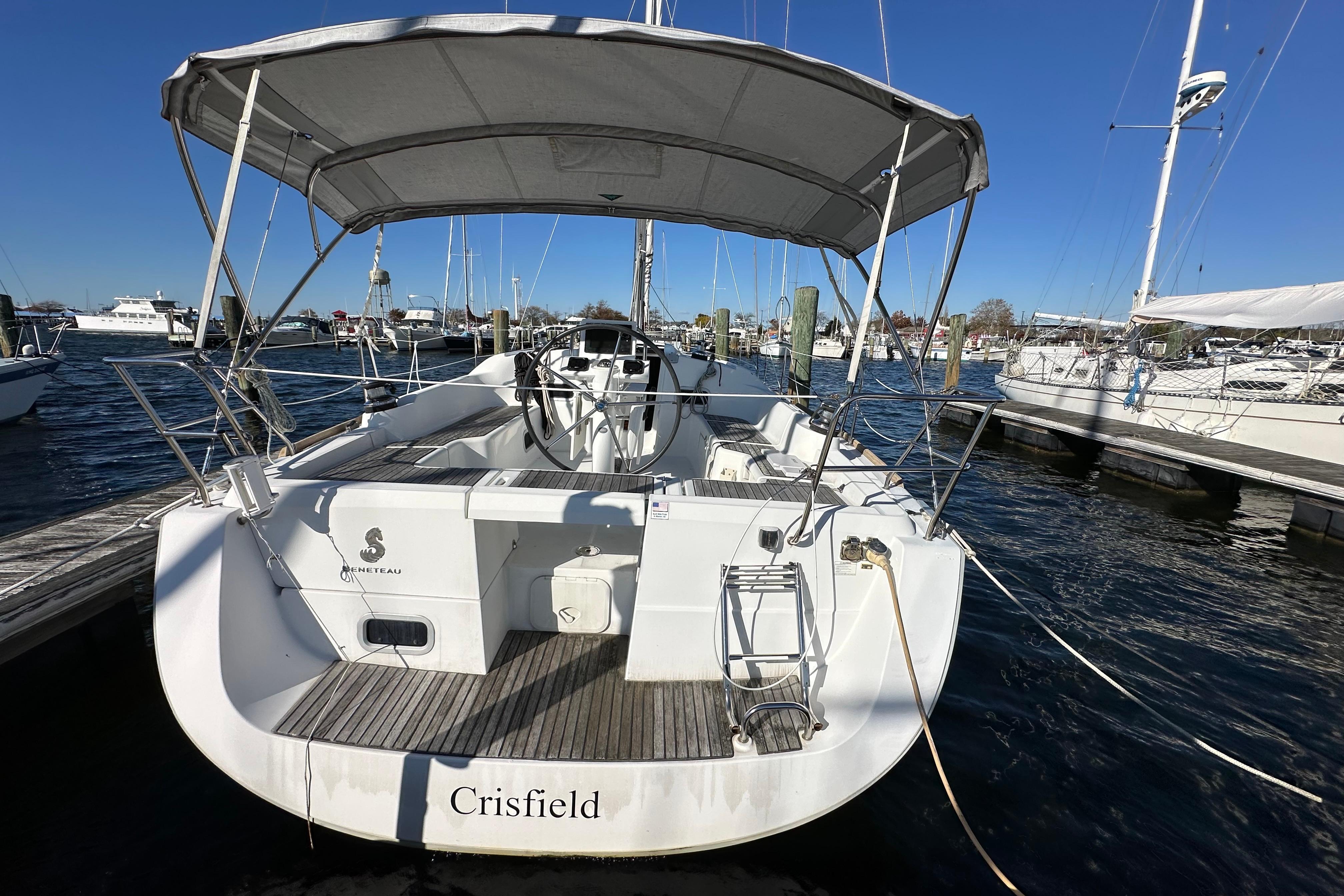 2015 Beneteau Oceanis 37 sailboat docked, rear view with canopy and steering wheel.