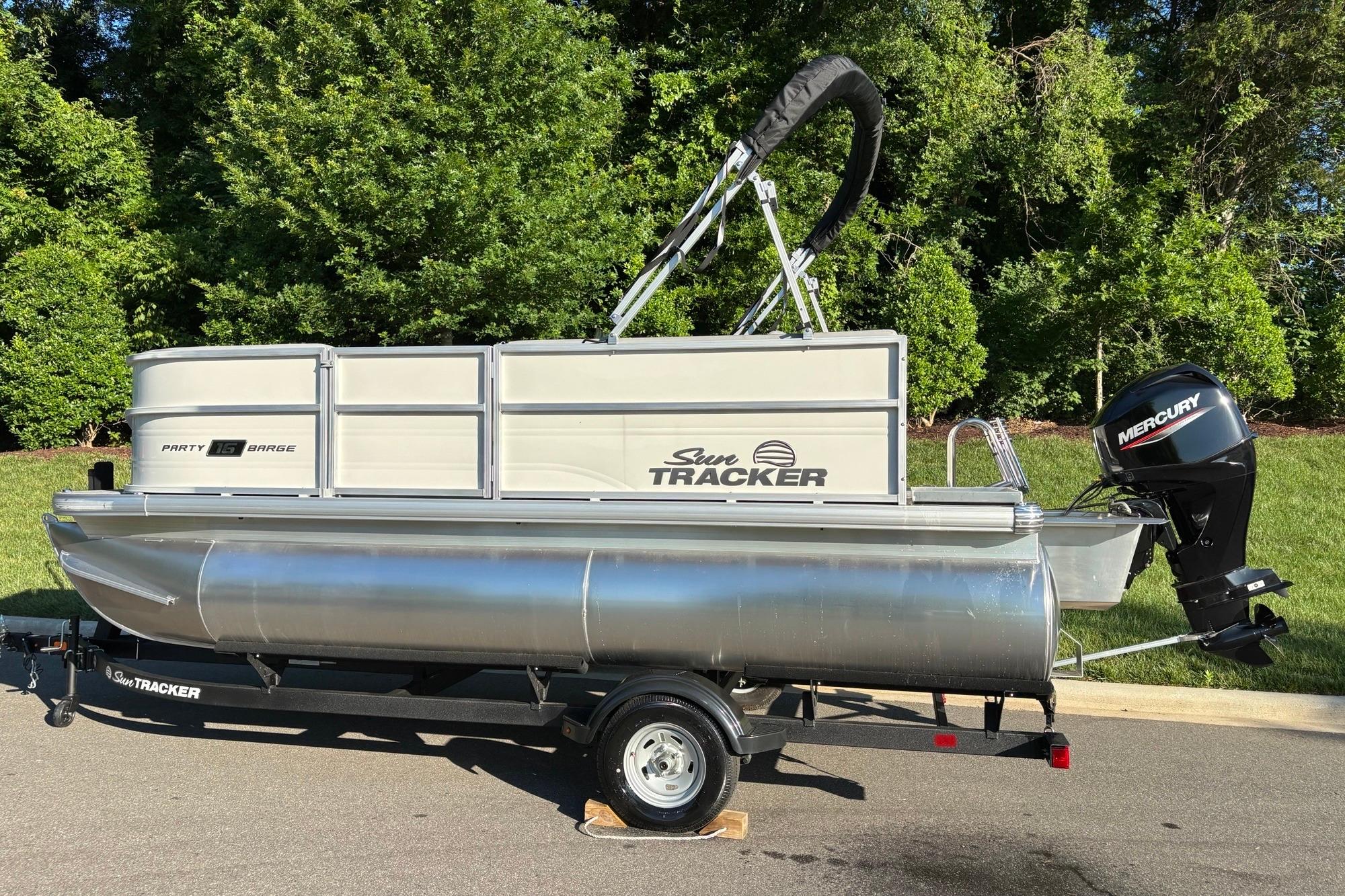 2026 Sun Tracker Party Barge 16 DLX pontoon boat on trailer, parked outdoors.