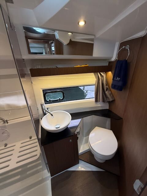 The image shows a modern boat bathroom with a sink, toilet, and mirror.