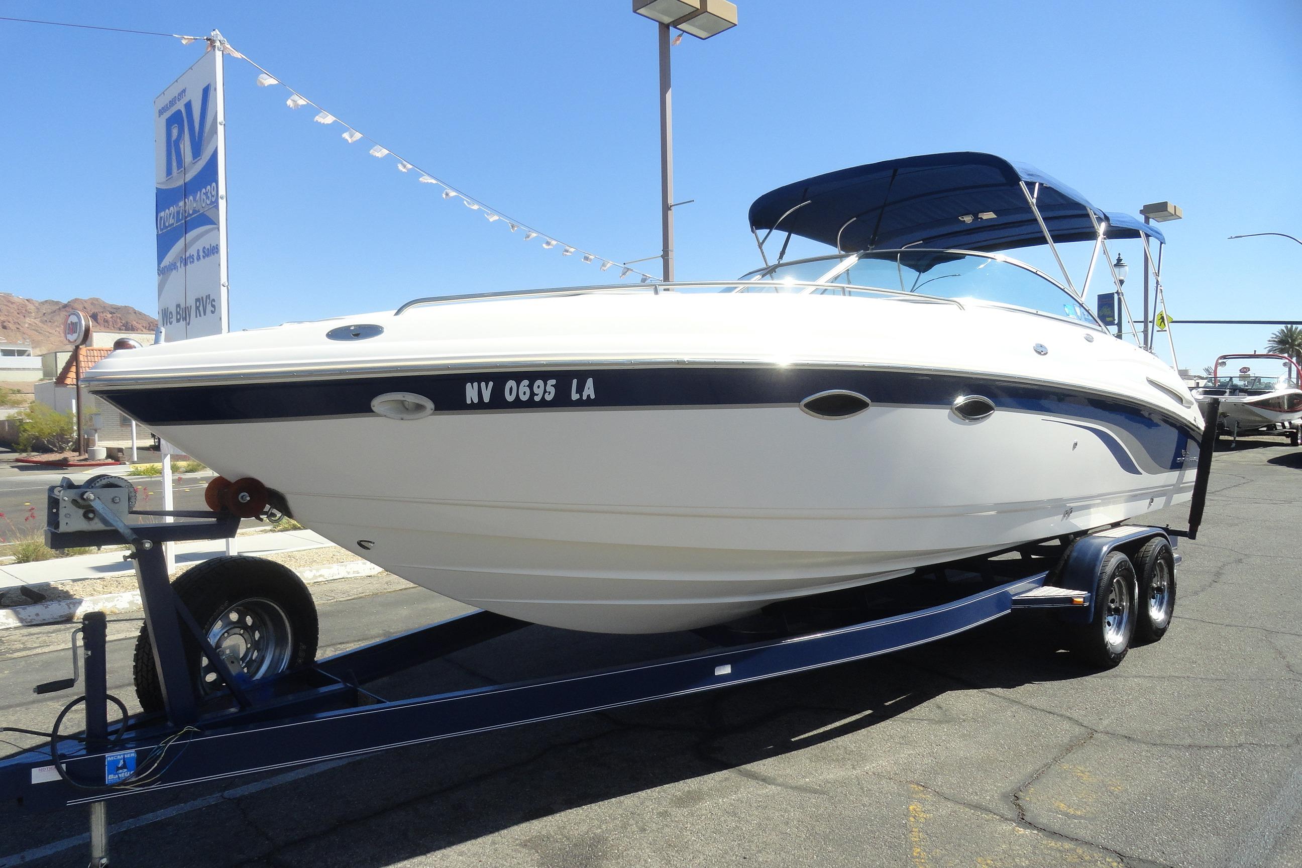 2001 Chaparral 265 SSi boat on trailer, parked outdoors under clear blue sky.