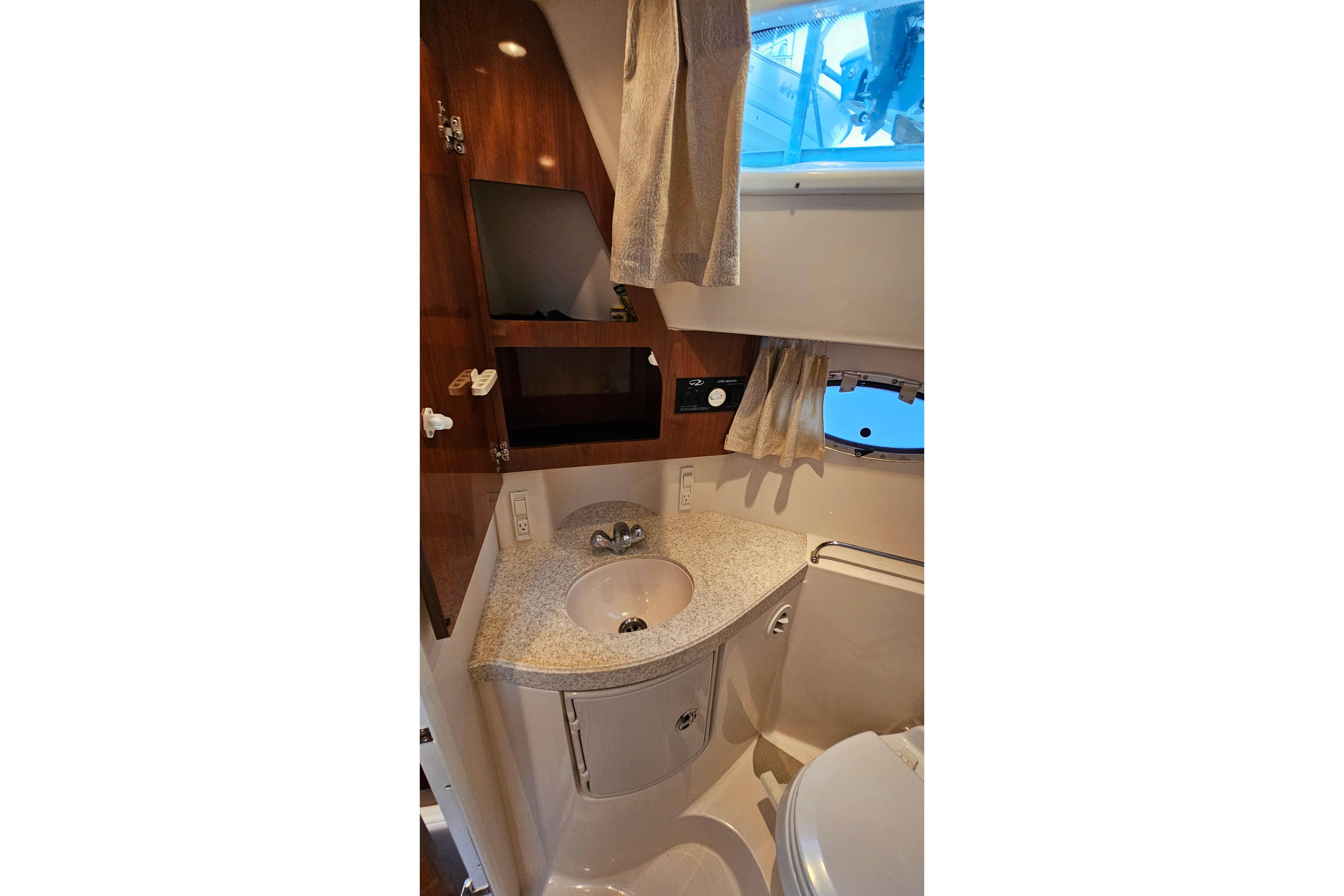 2005 Regal 3060 Window Express bathroom with sink, mirror, and porthole window.