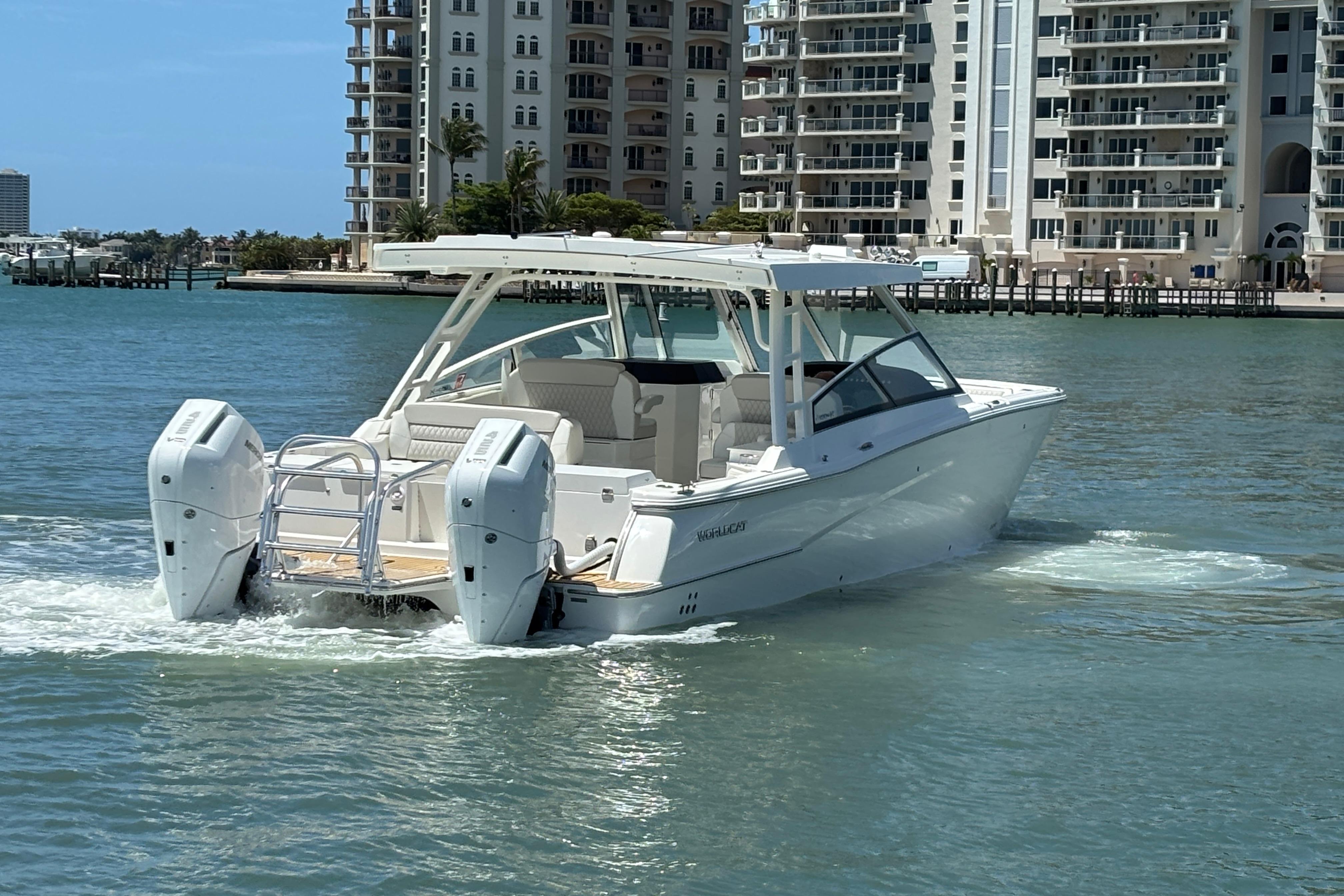2026 World Cat 400 DC-X Island boat cruising near waterfront buildings.