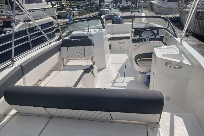 2023 Bayliner DX 2200 boat interior with seating and steering wheel at a marina.