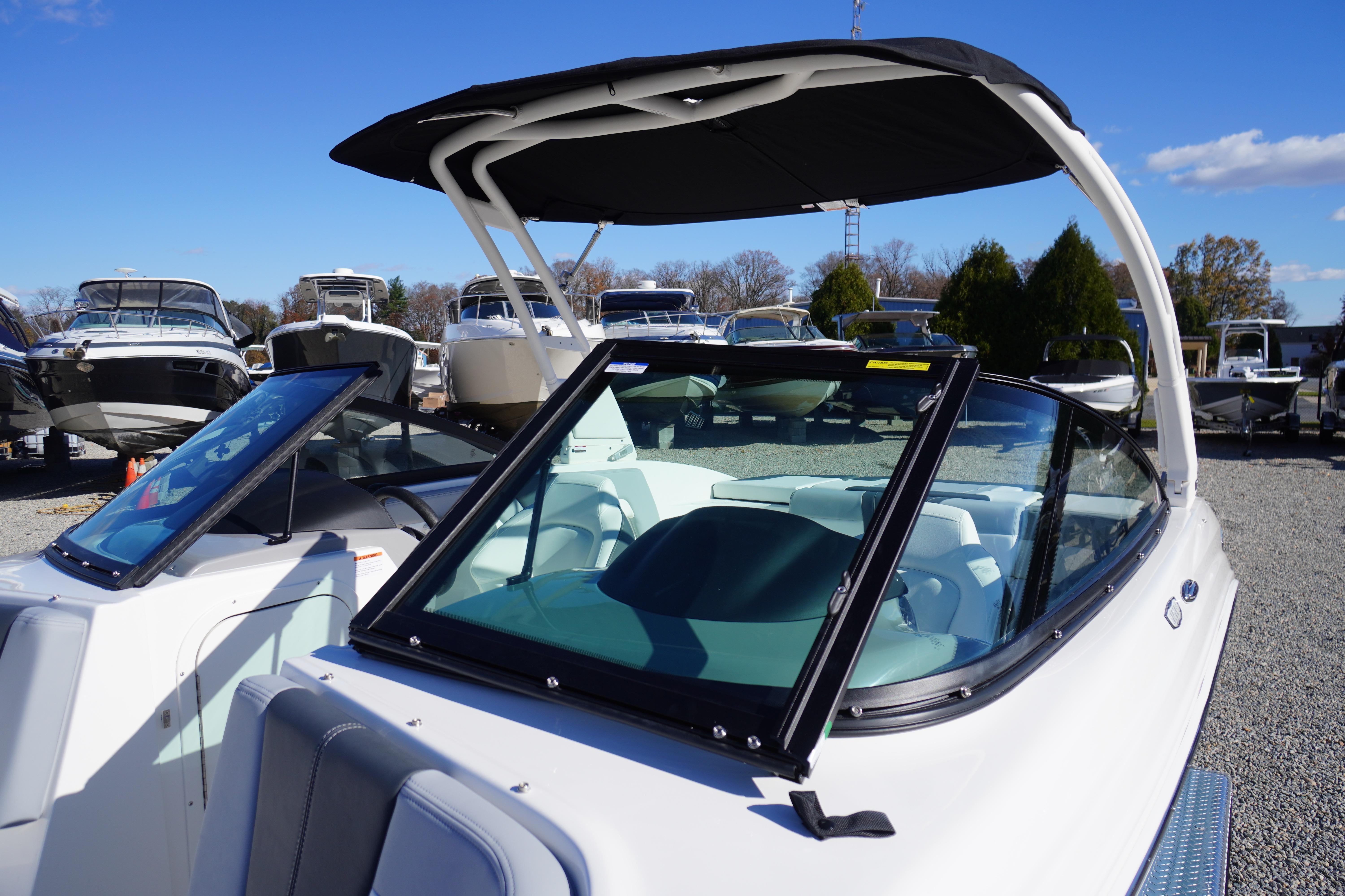 2026 Chaparral 23 SSi boat with sleek design and black canopy, displayed outdoors.