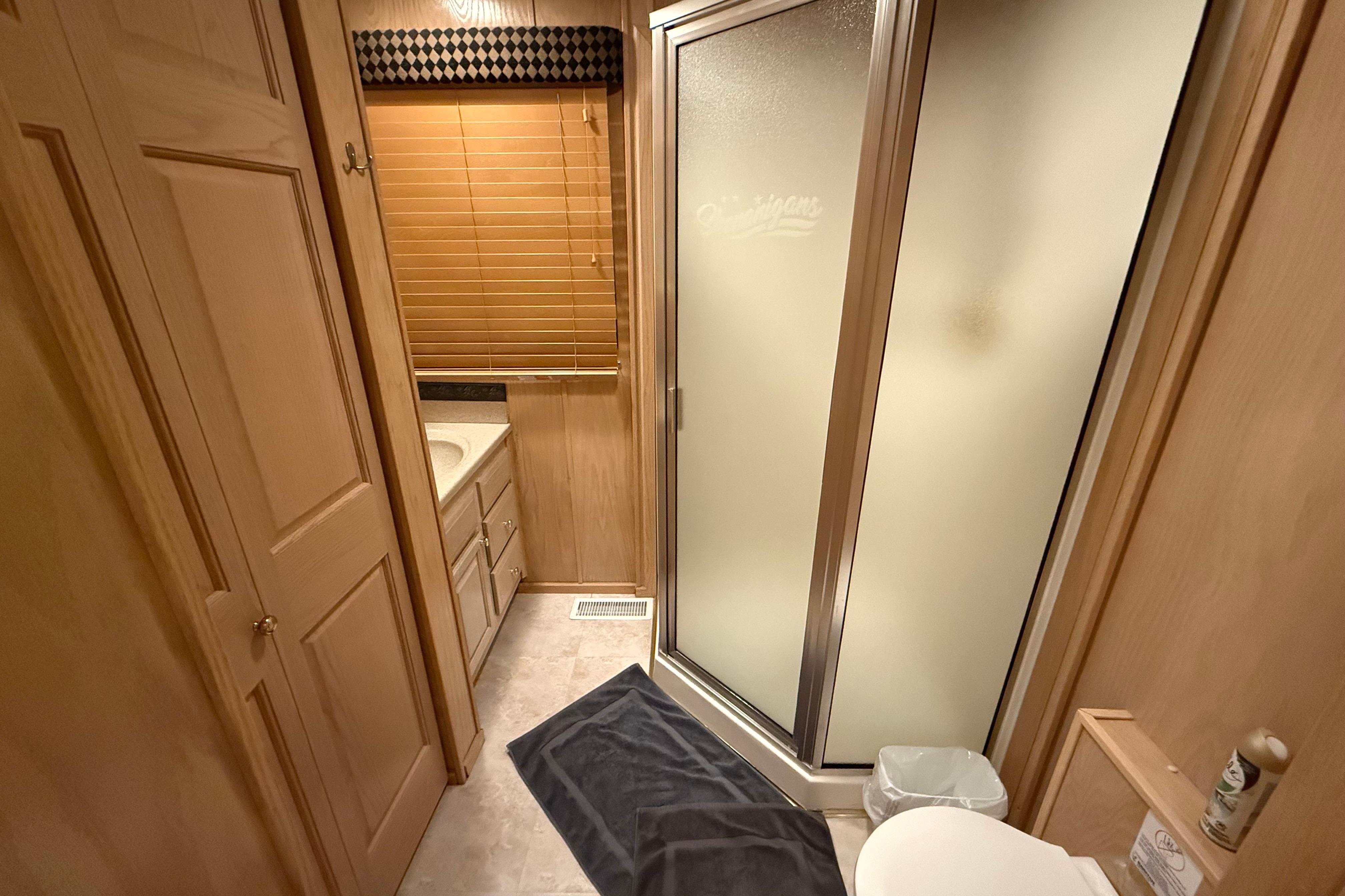 Bathroom interior of a 1998 Sumerset 16x76 houseboat with shower and wooden cabinetry.