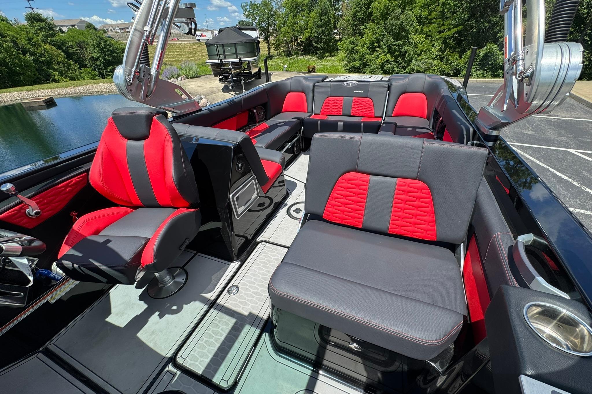 2021 MasterCraft X26 boat interior with red and black seating, docked by a scenic lake.