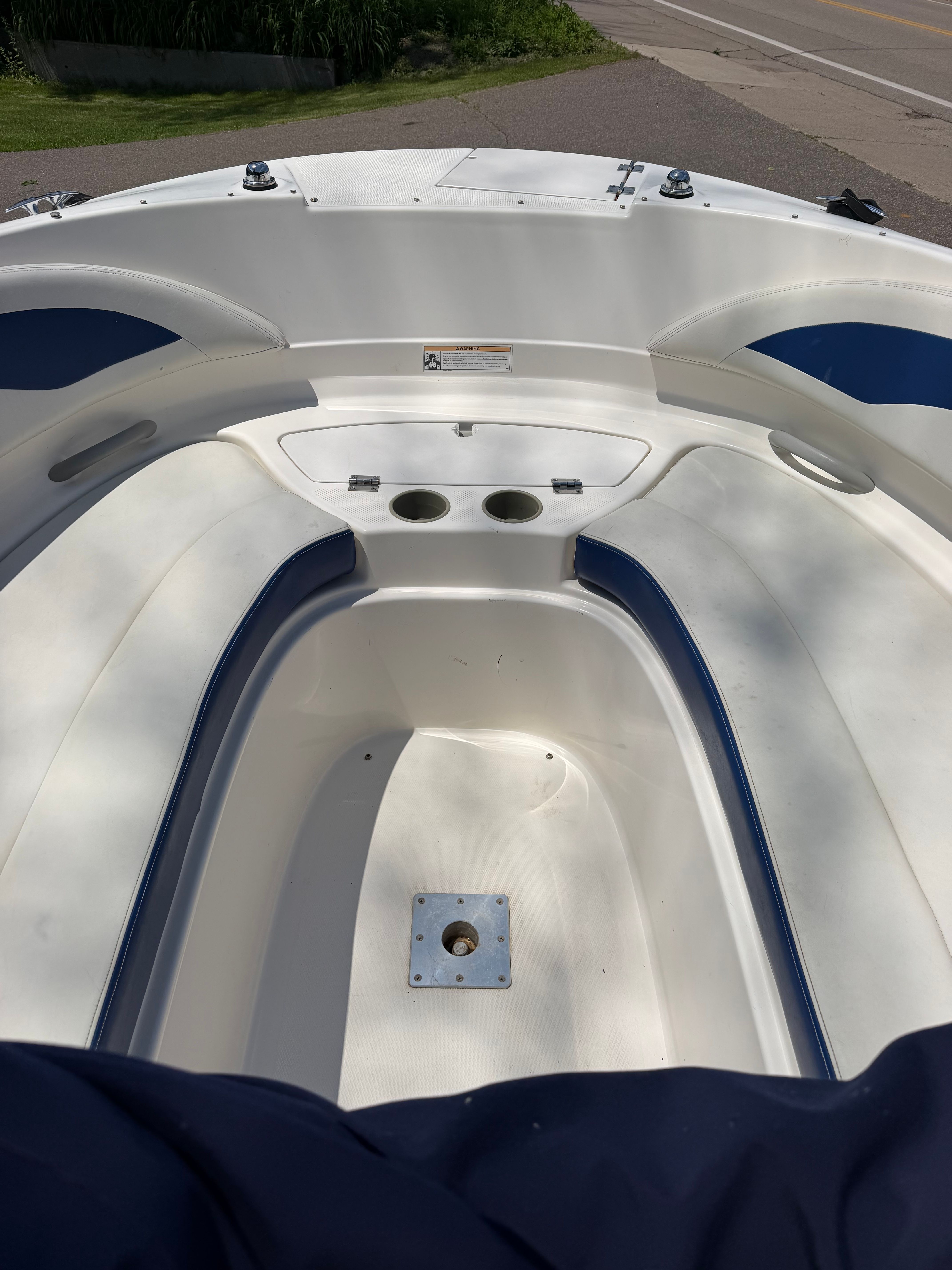 The image shows the open bow of a 2005 Bayliner 212 boat with seating and cup holders.
