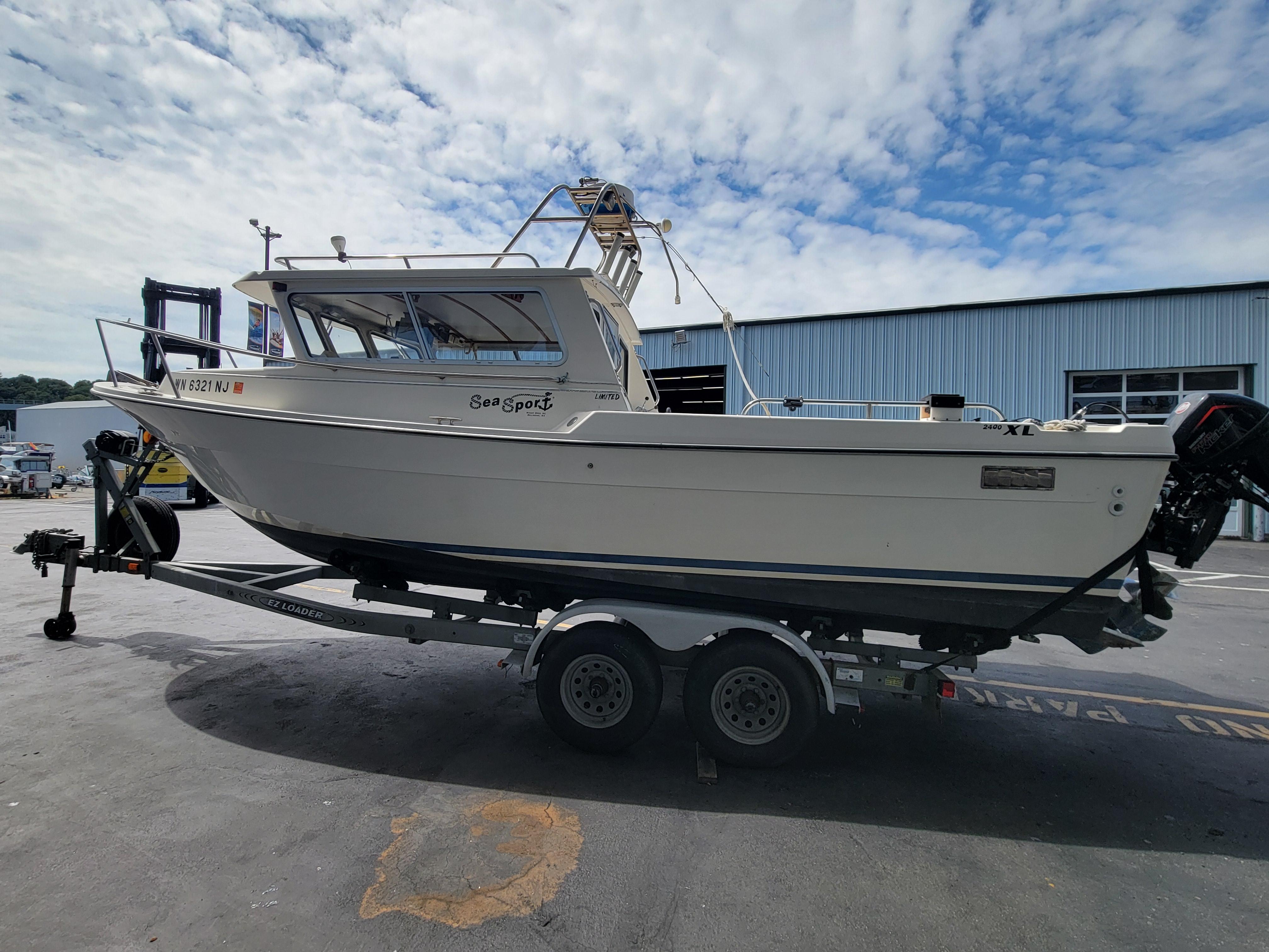 1999 SeaSport 2400 XL Limited boat on trailer, parked outdoors under cloudy sky.