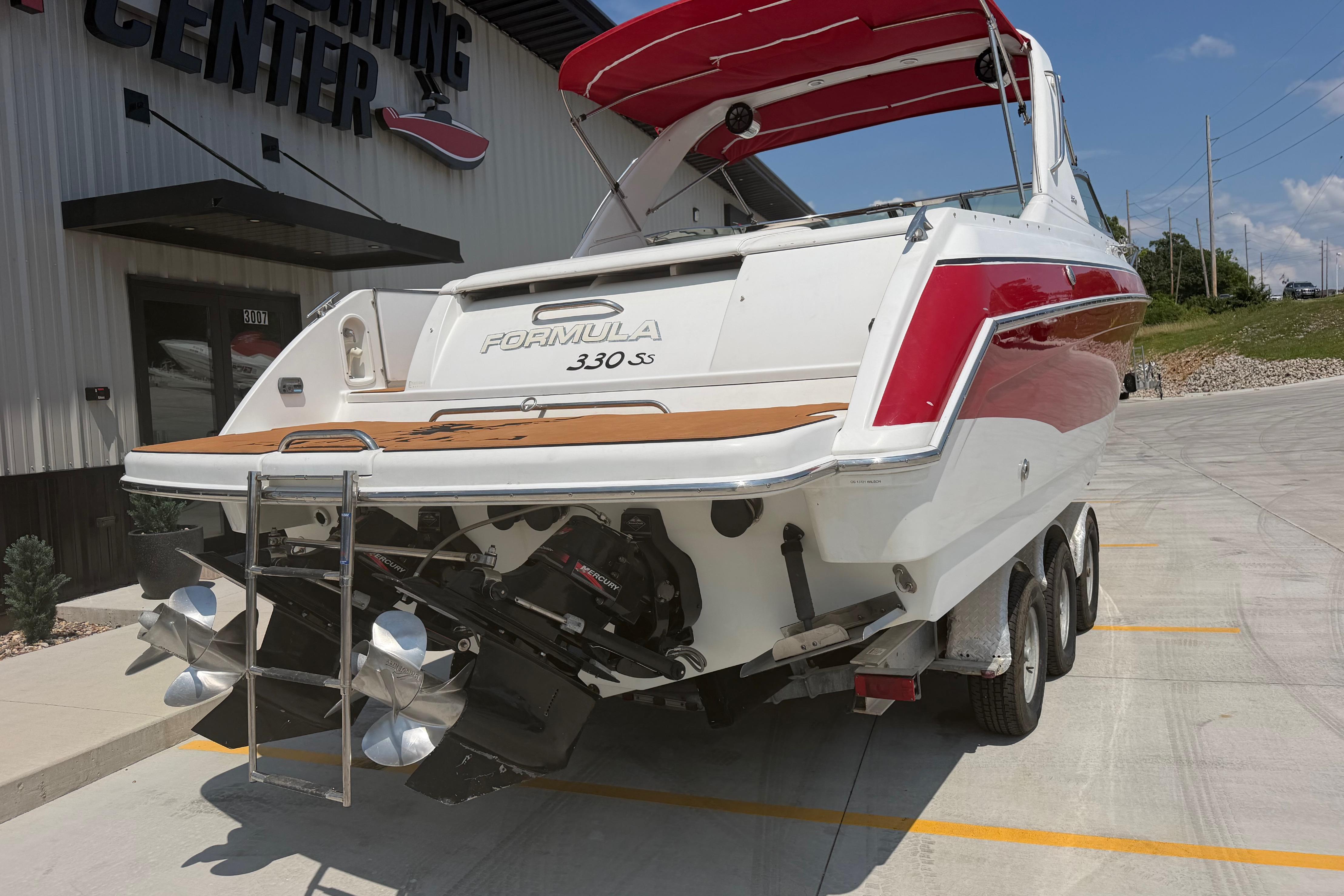 2006 Formula 330 Sun Sport boat on trailer, red and white design, outside a boating center.