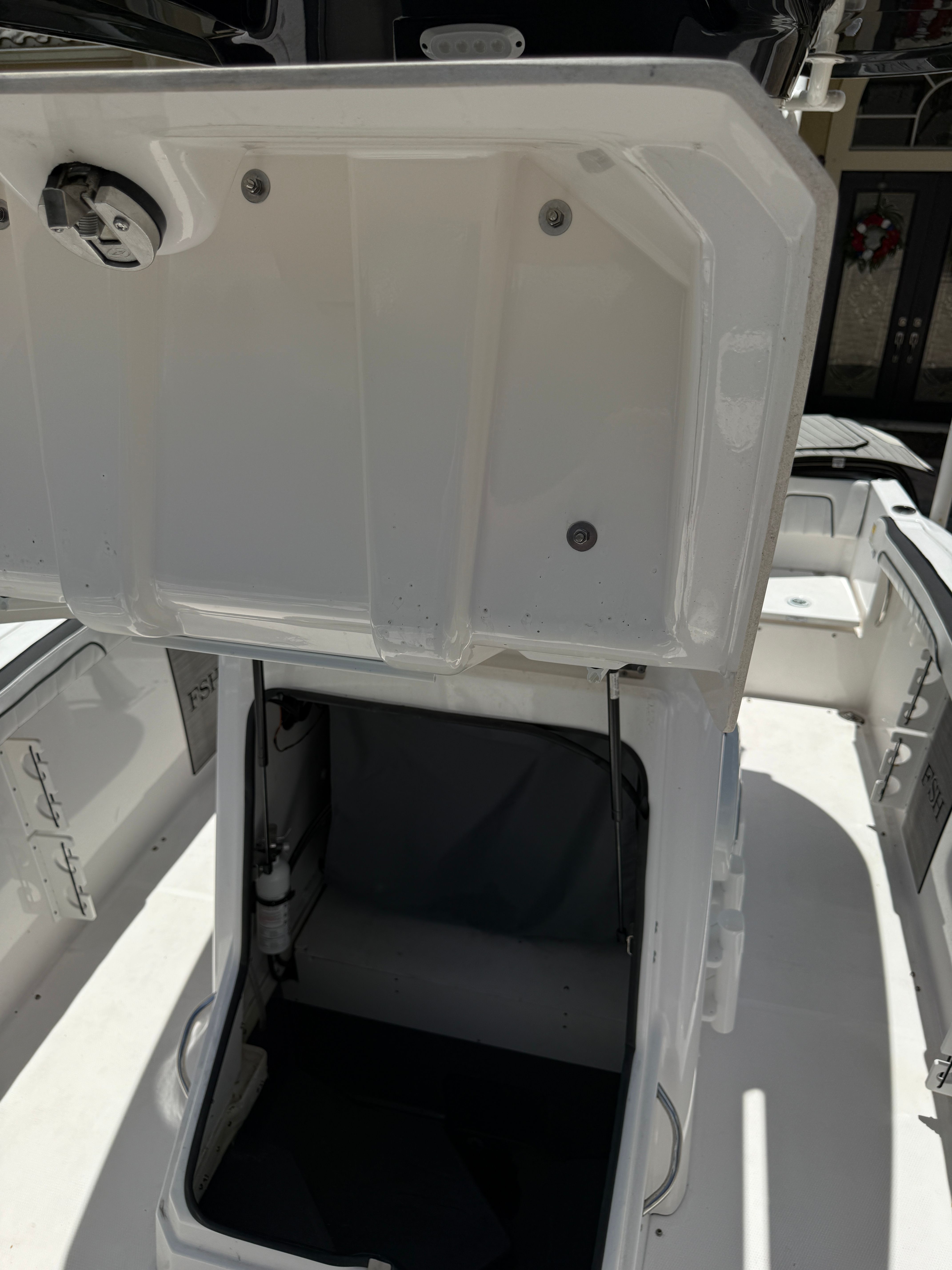 An open storage compartment on a 2024 Yamaha 252 FSH Sport boat.