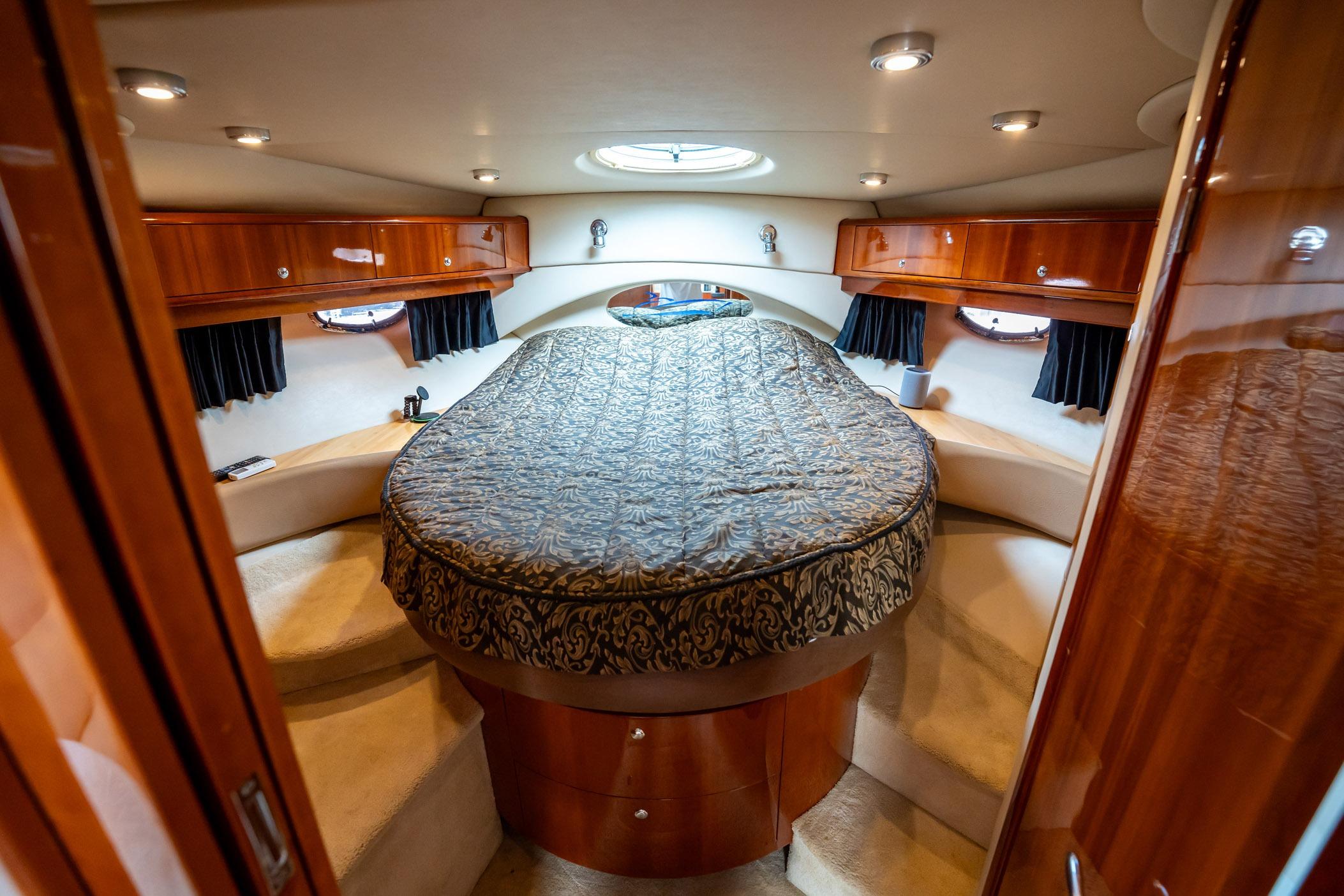 Luxurious 2008 Regal Commodore 4460 yacht cabin with elegant wood finish and cozy bedding.