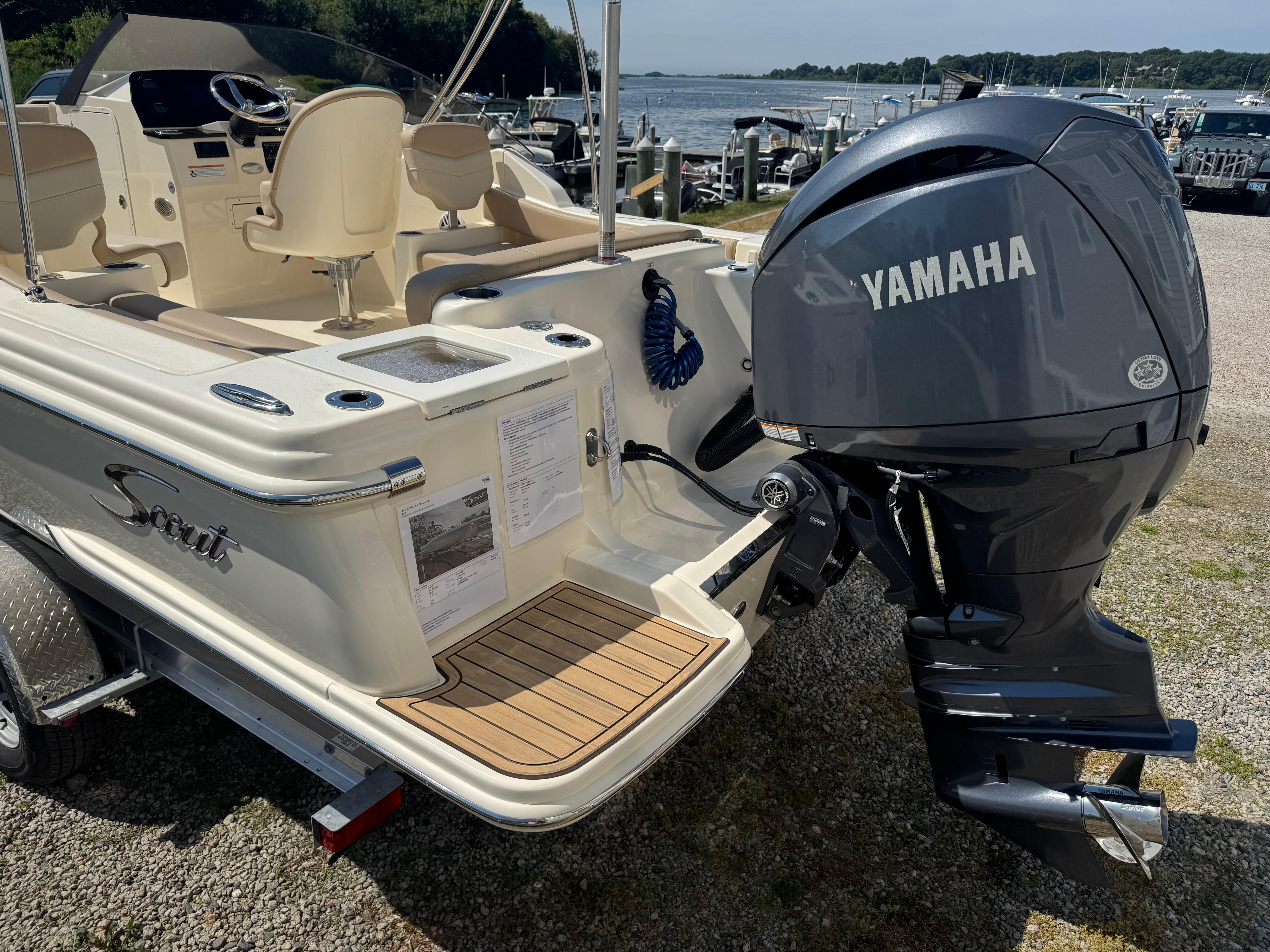 2025 Scout 215 Dorado boat with Yamaha outboard motor, docked near a scenic waterfront.