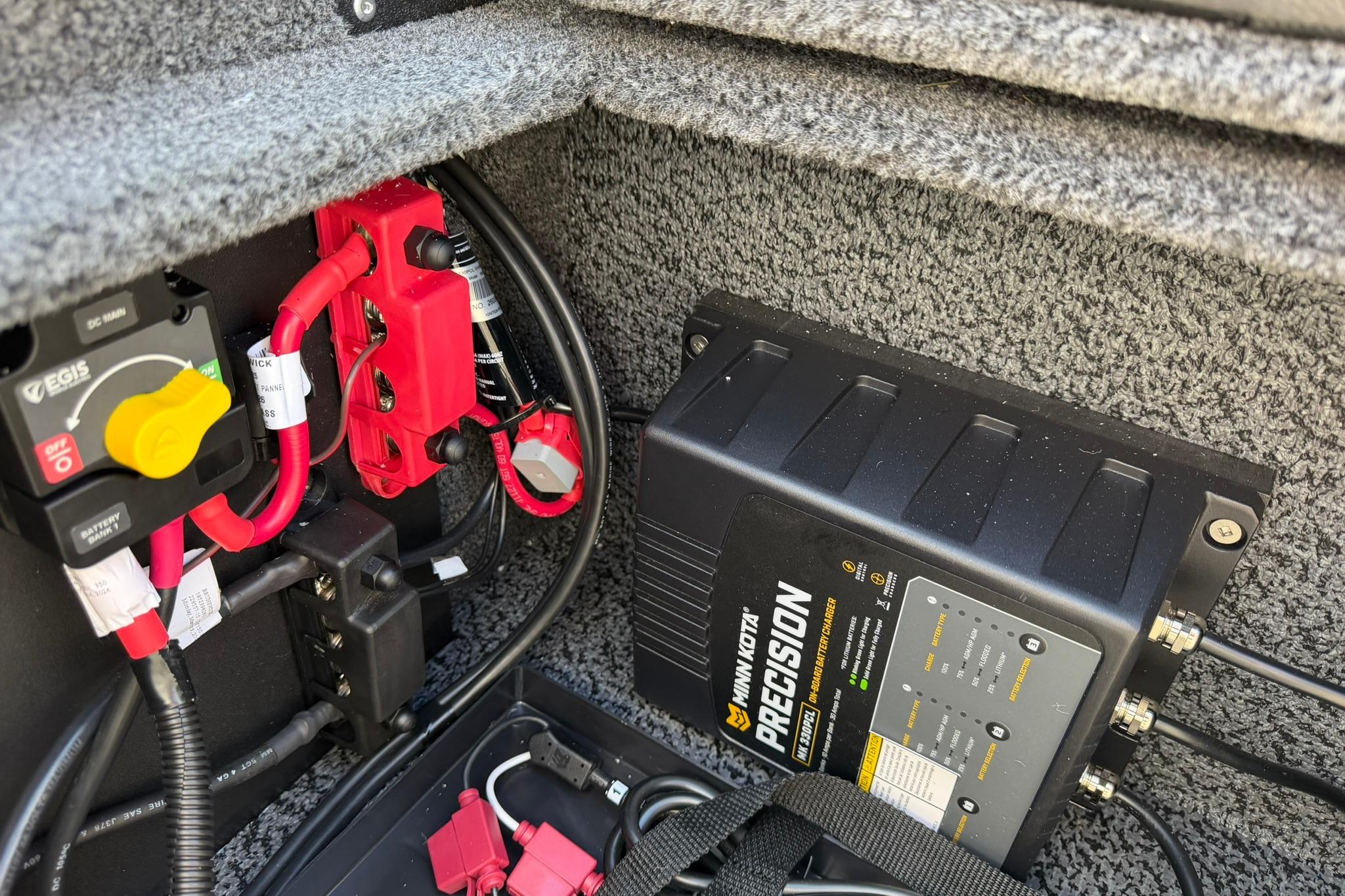 Electrical components inside a 2027 Lund 1775 Crossover XS boat, featuring a Minn Kota Precision charger.
