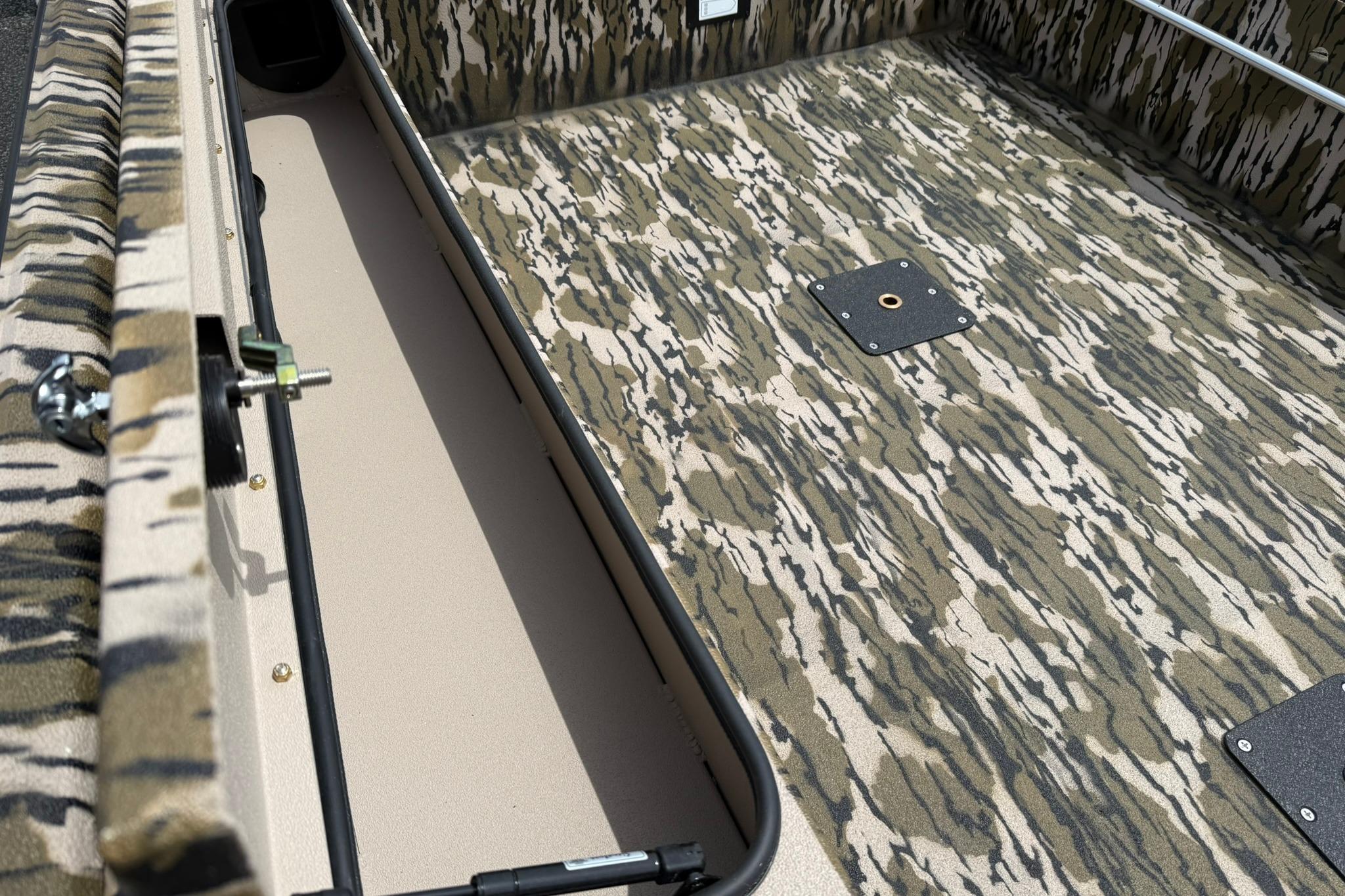Camouflage interior of 2026 Avid 16 Commander boat, featuring textured flooring and storage compartment.