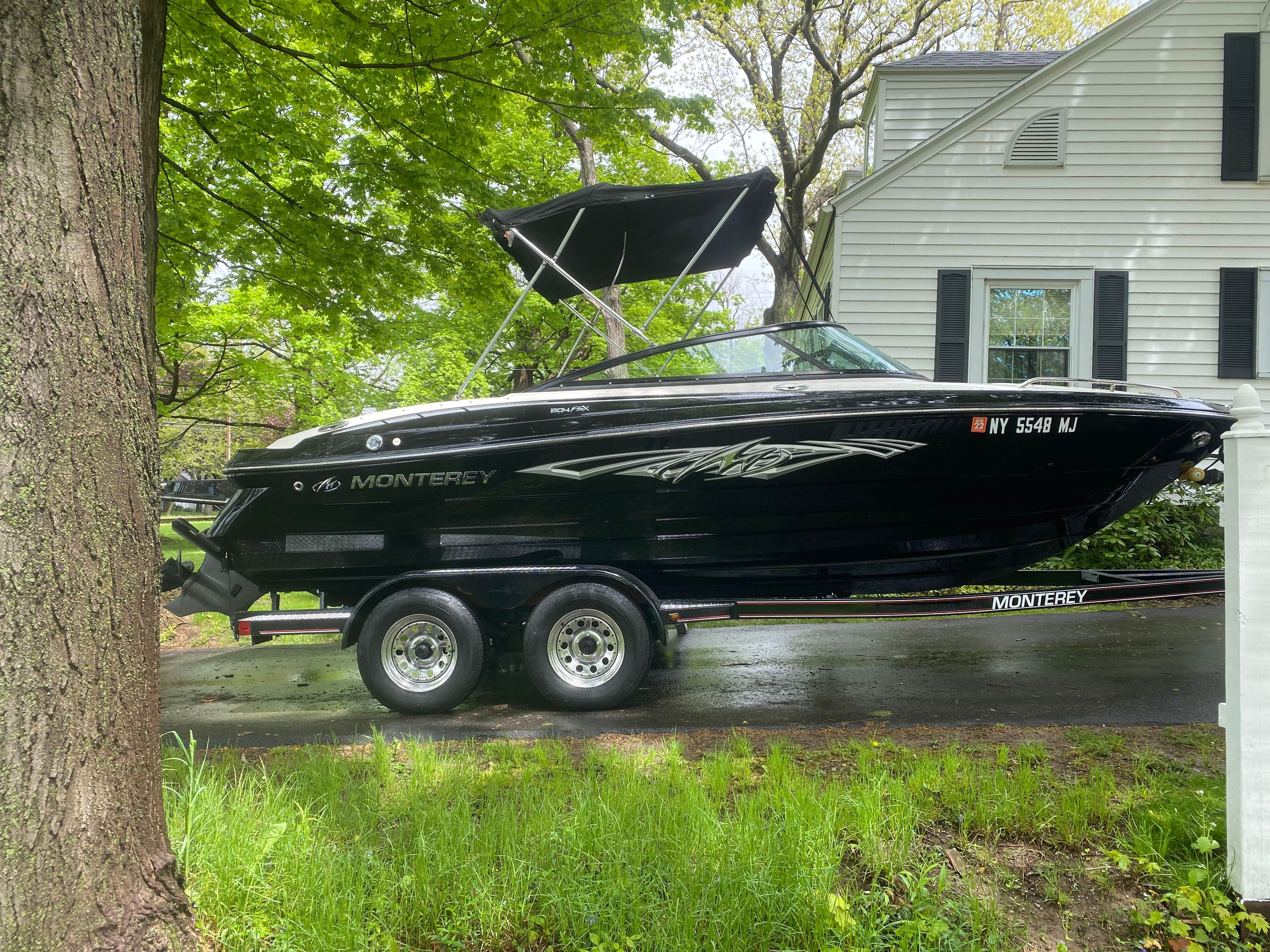 Black 2013 Monterey 204FSX boat on trailer in front of house.