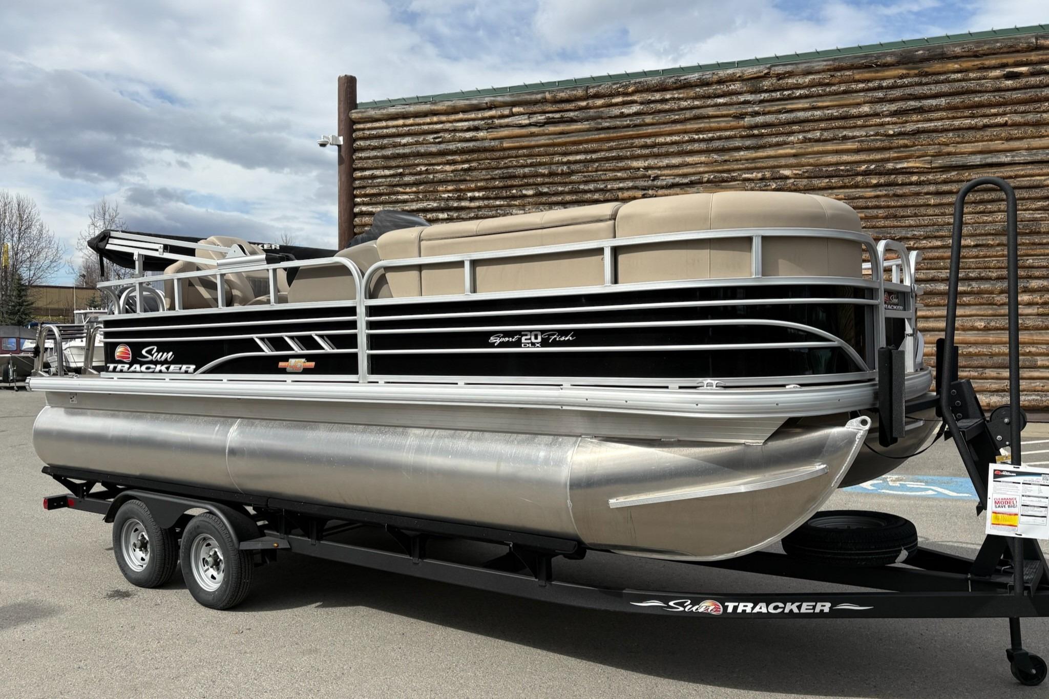 2023 Sun Tracker SportFish 20 DLX pontoon boat on trailer, parked outdoors.