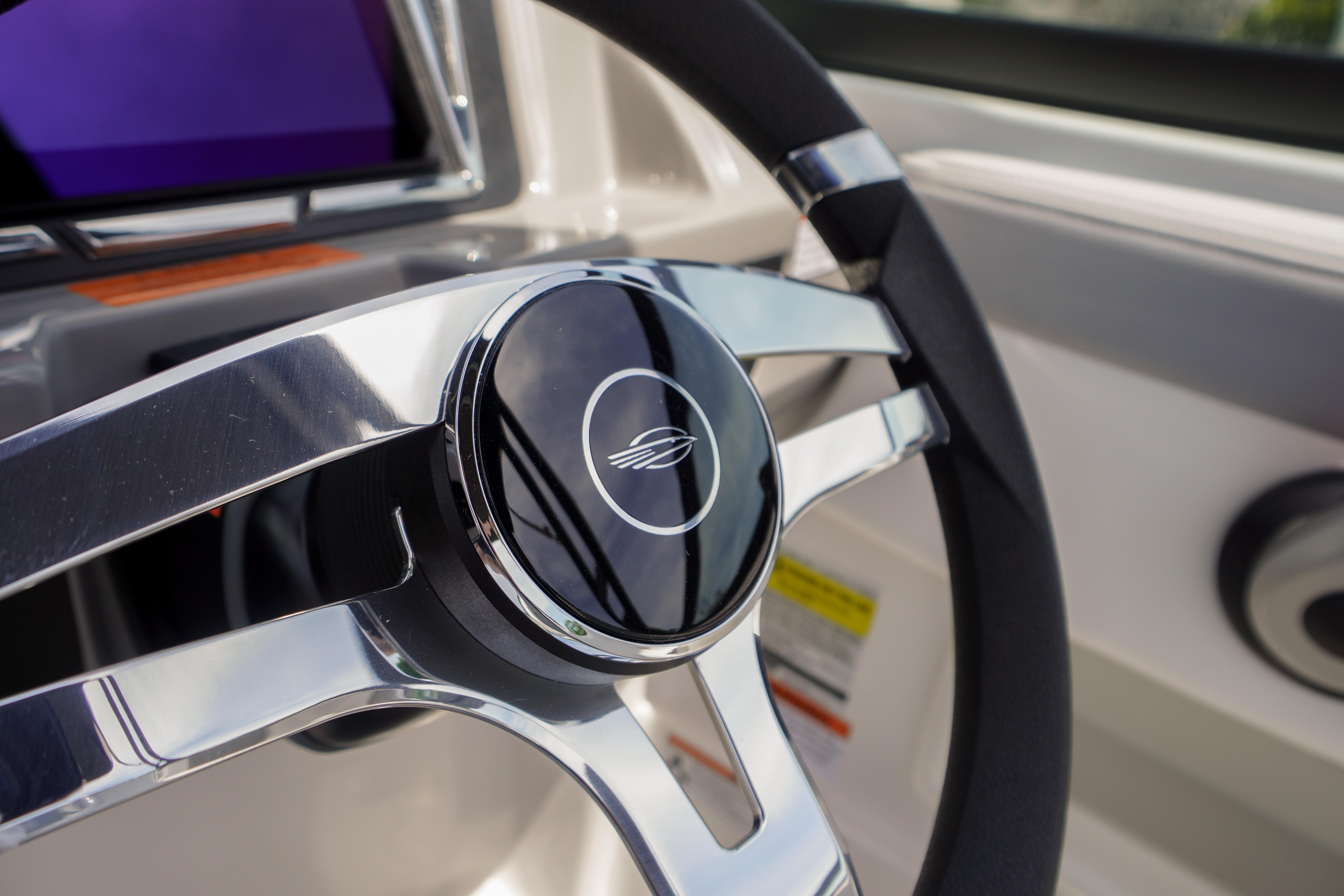 Steering wheel of 2026 Chaparral 23 SSi OB boat, featuring sleek chrome design.