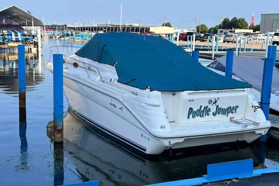 1996 Sea Ray 270 Sundancer boat named "Puddle Jumper" docked with blue cover.
