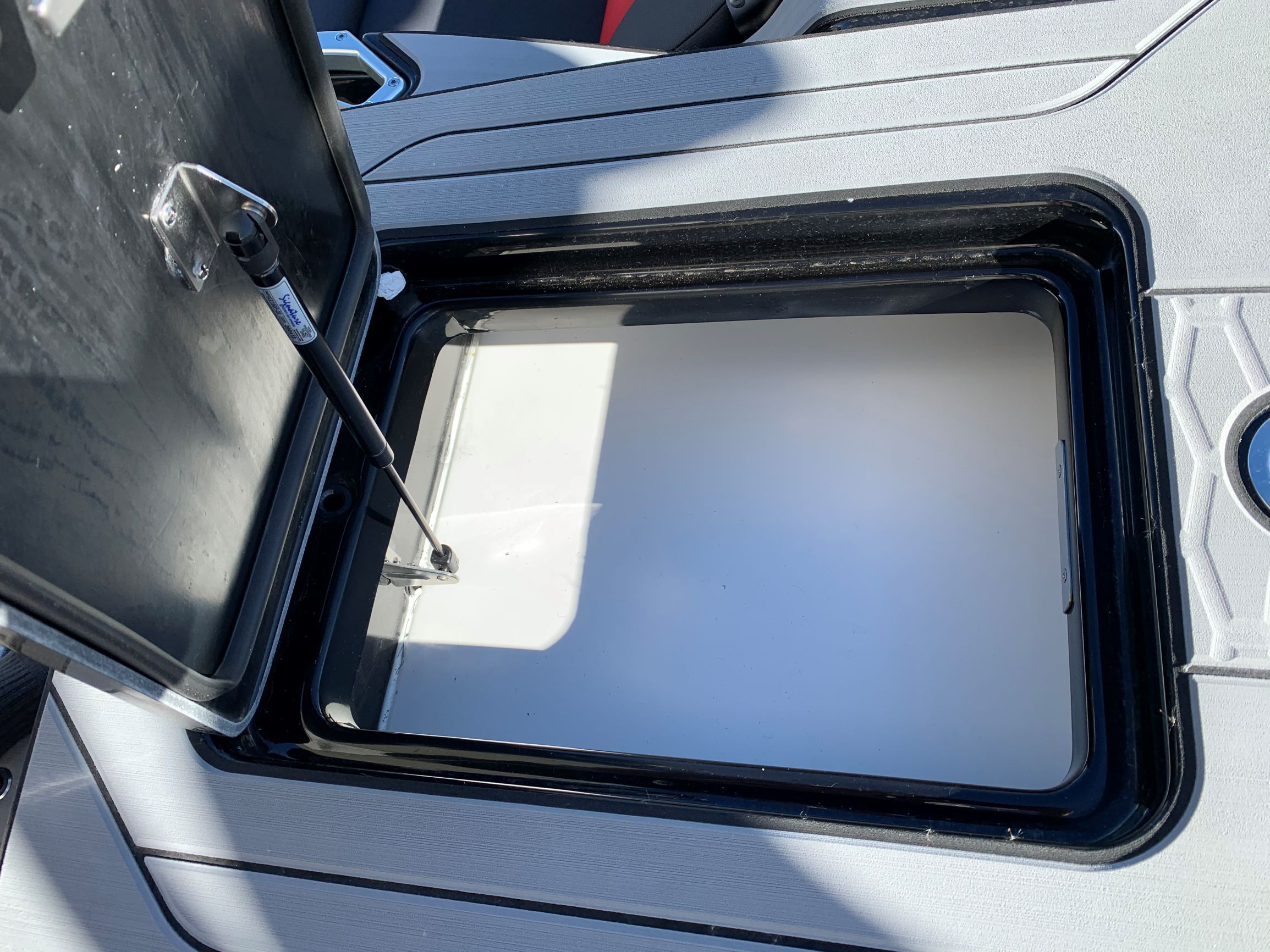 Open storage compartment lid on a boat with hydraulic support.