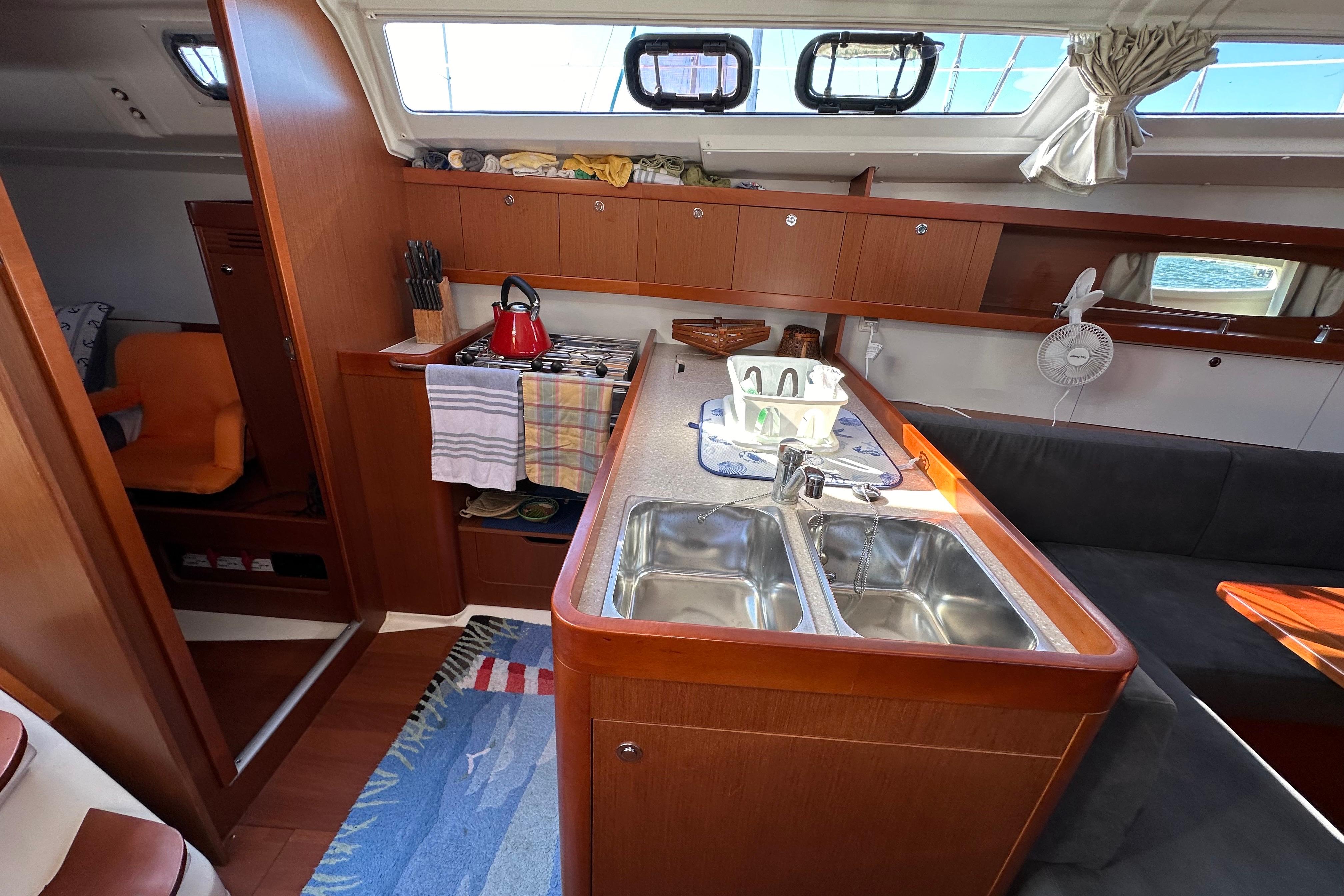 Interior of 2015 Beneteau Oceanis 37 yacht, featuring a cozy kitchen and seating area.