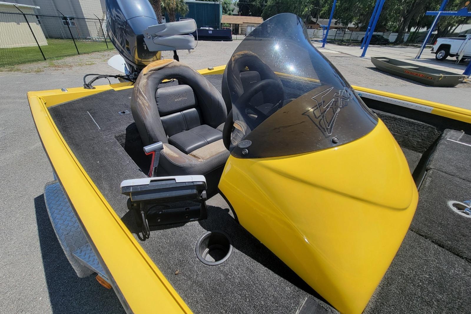 Yellow 2011 Excel 1751 F4 boat with windshield and seating, parked outdoors.