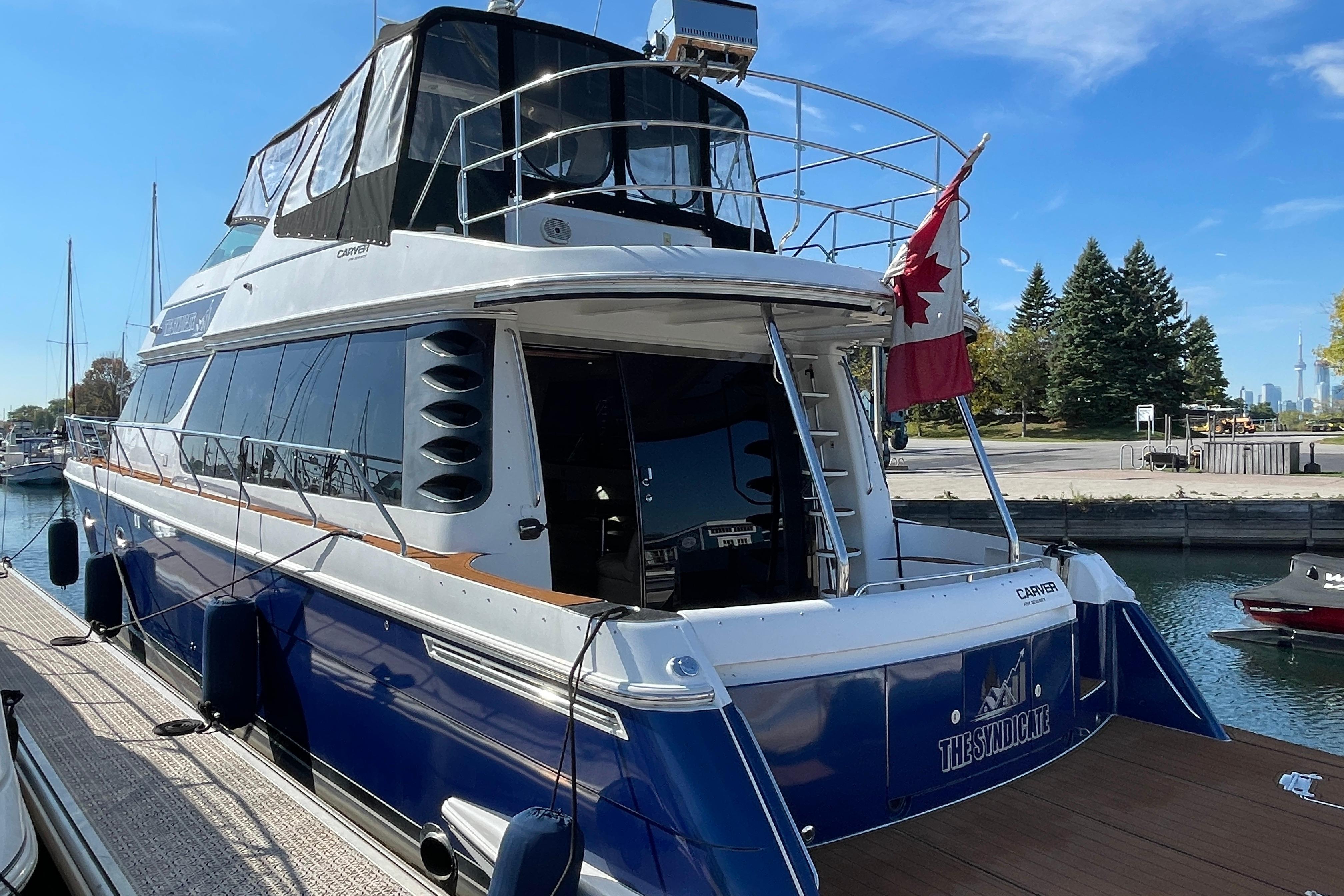 2002 Carver 570 Voyager Pilothouse yacht docked with Canadian flag, sunny day.