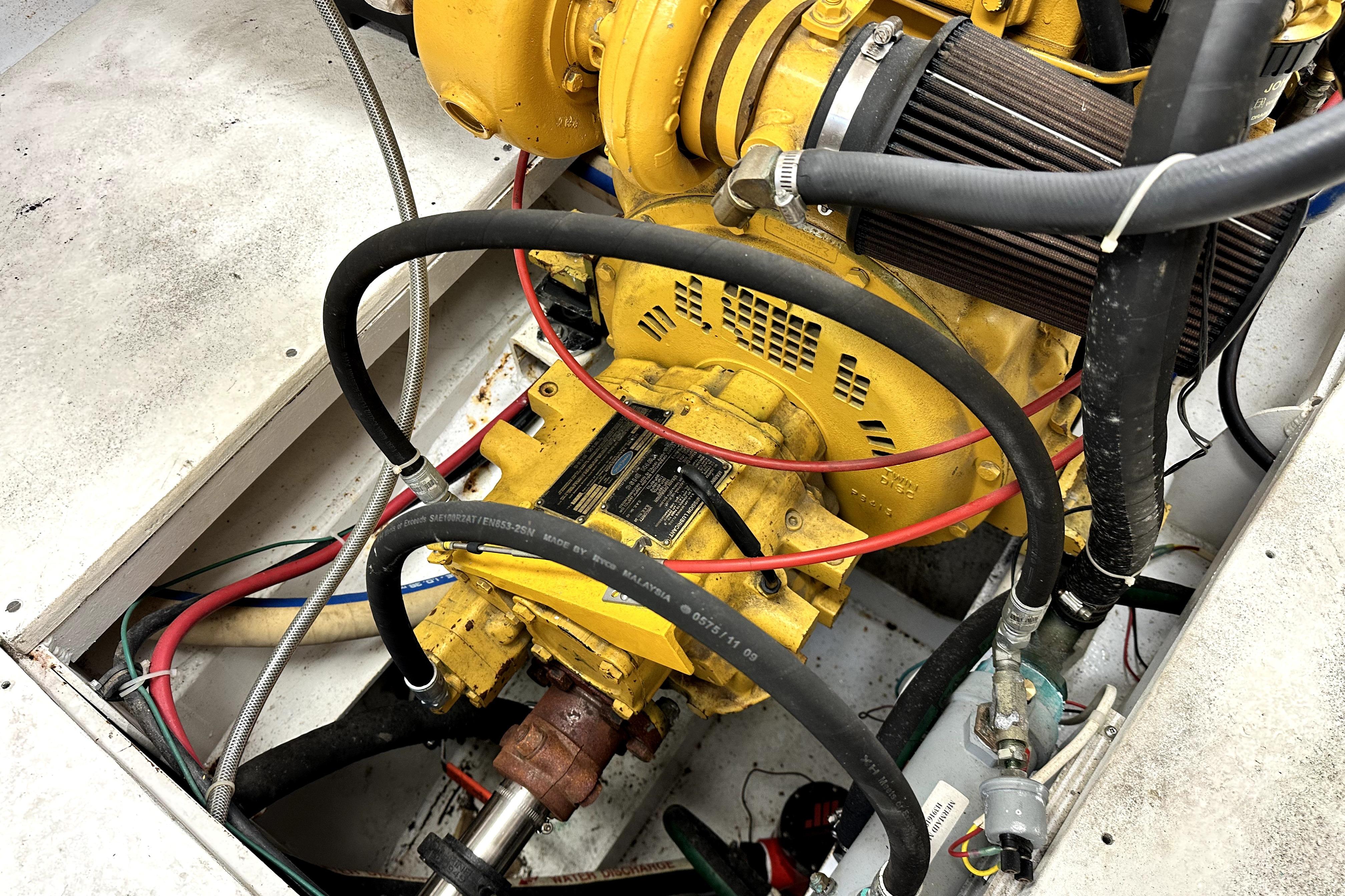 Engine compartment of a 2012 Custom Pacific Northwest 43 boat, featuring yellow machinery and hoses.