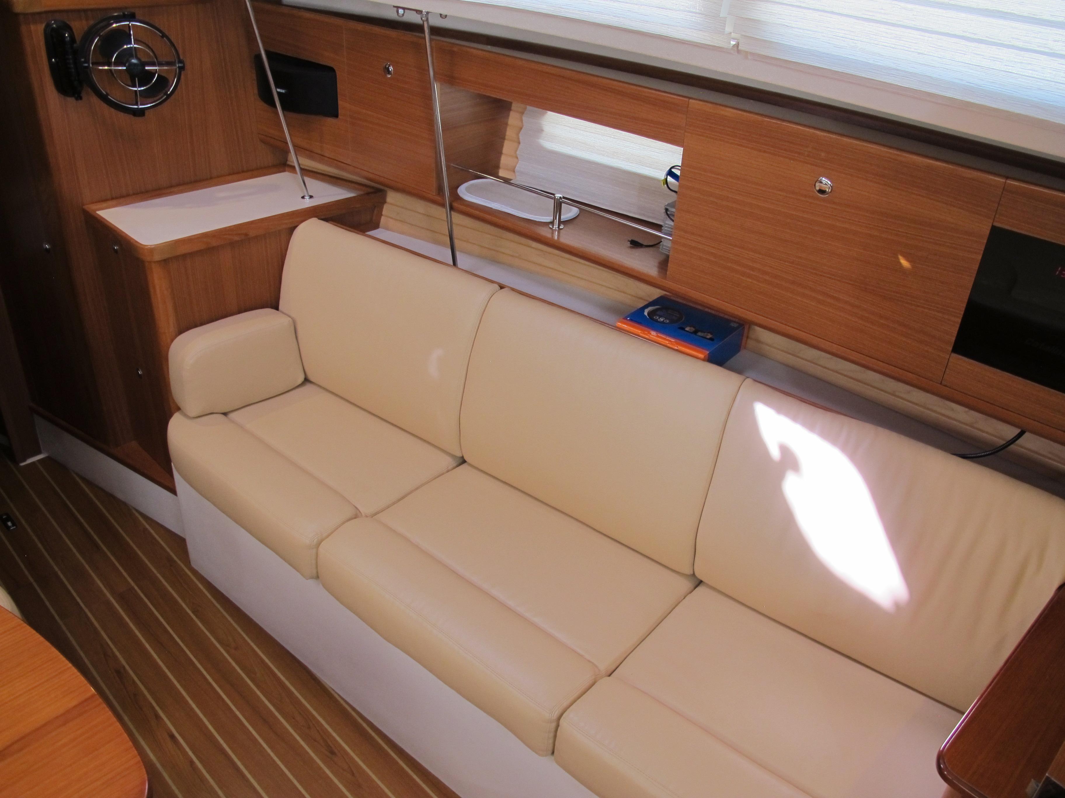 Interior of 2020 Catalina 315 sailboat with beige leather sofa and wooden cabinetry.