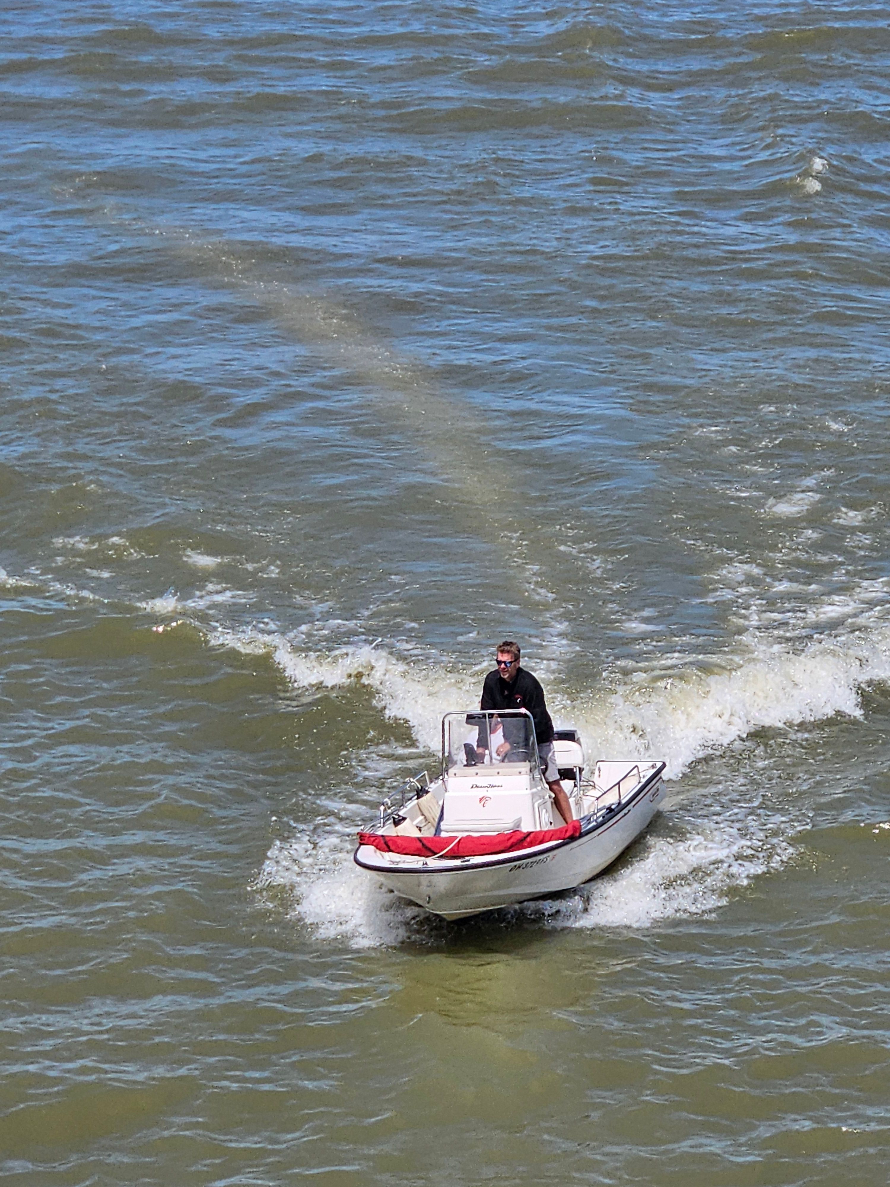 A small motorboat navigates choppy waters with one person at the helm.