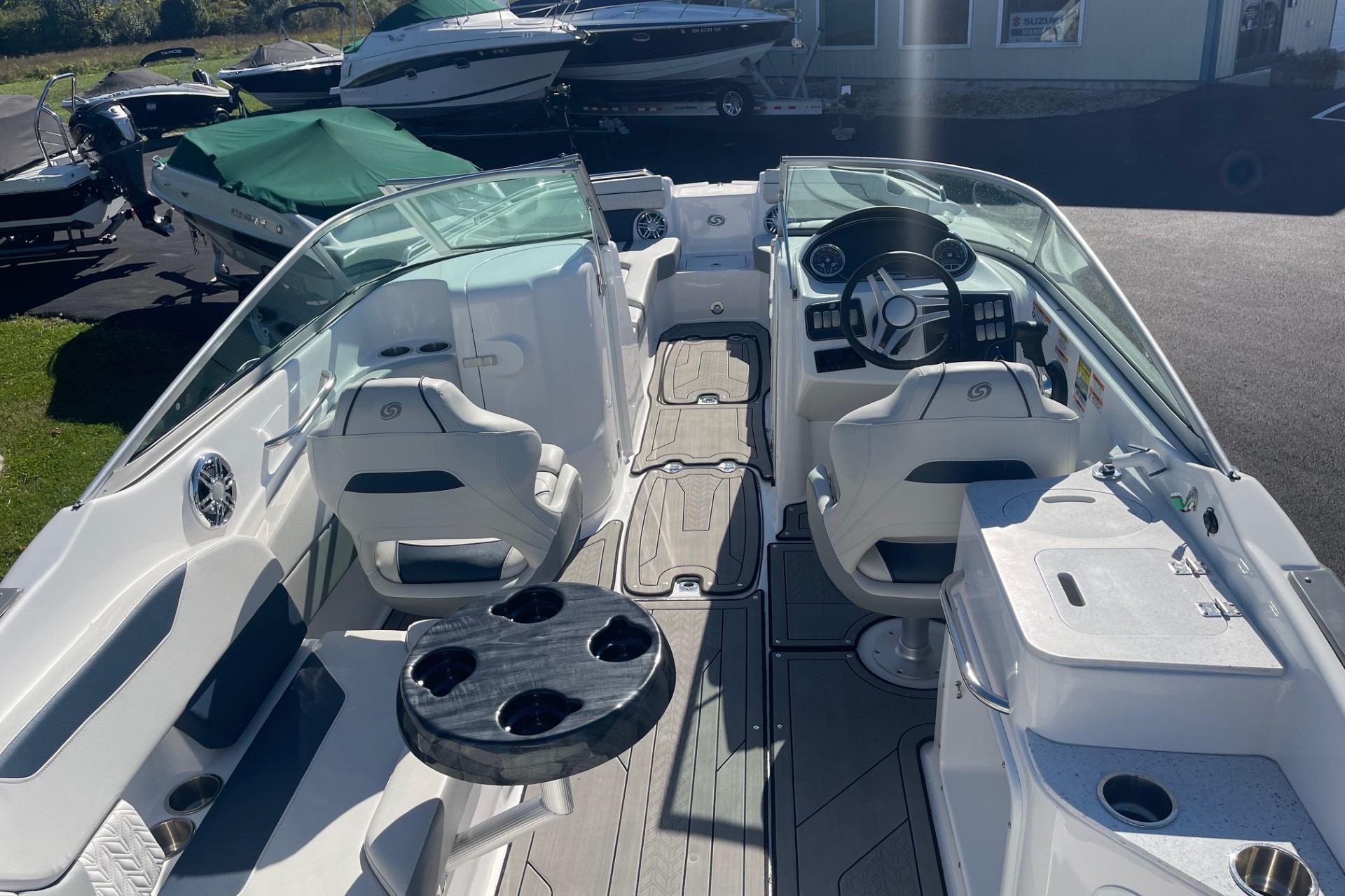 2023 Hurricane SunDeck 2400 OB boat interior with seating, steering wheel, and table.