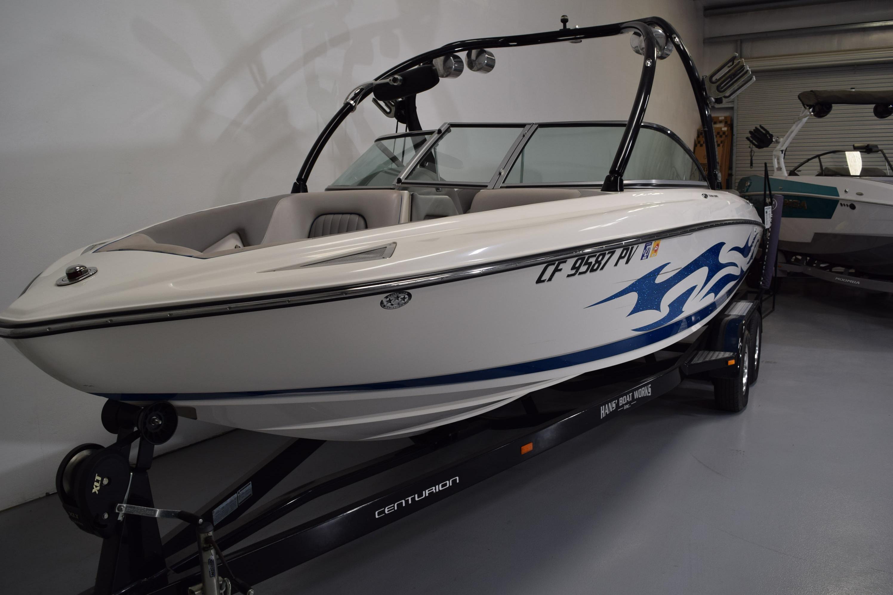 2007 Centurion SV 240 boat with blue graphics on trailer in showroom.