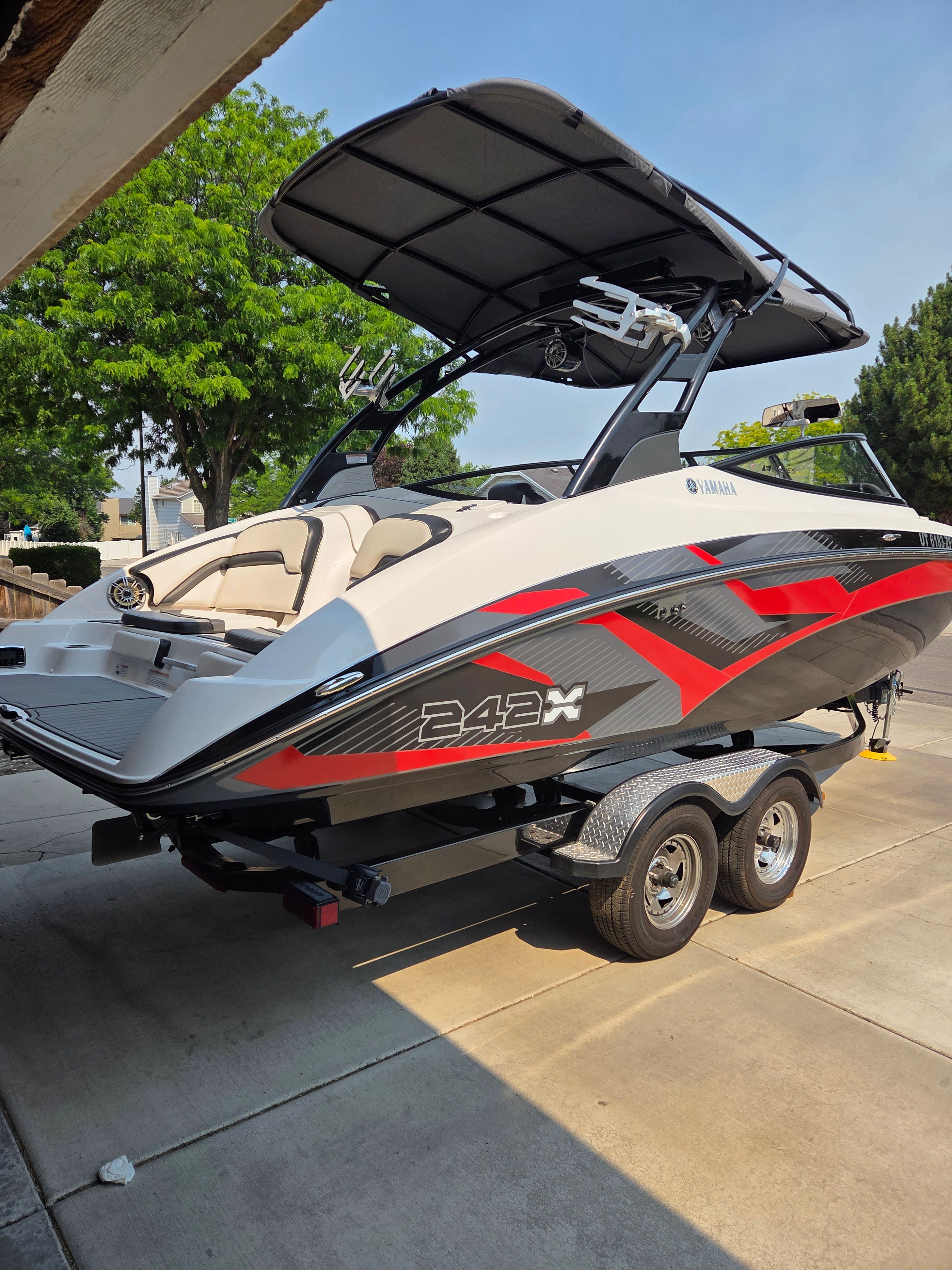 A 2016 Yamaha 242X E-Series boat on a trailer in a driveway.